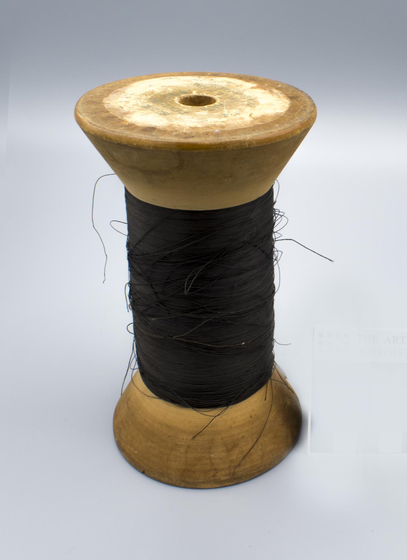 Image of Large spool of black thread, used by Seattle's first childrens' tailor, ca. 1915