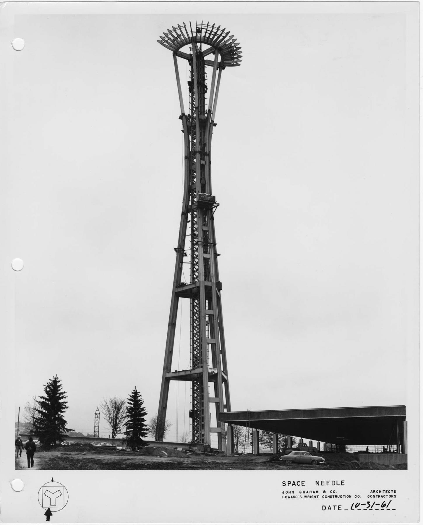 Image of Space Needle under construction, showing partial installation of restaurant ring girder with “sunburst” vanes, October 31, 1961