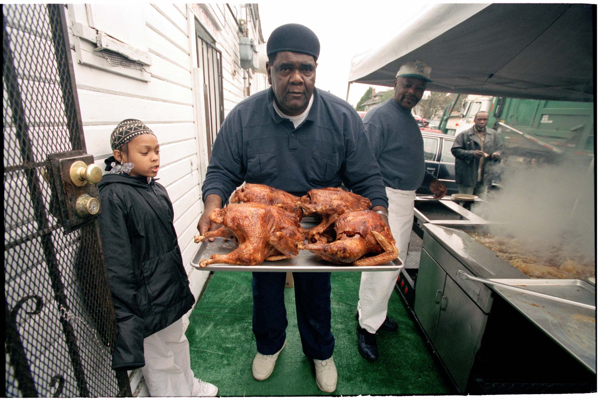 Image of Henry Williams carrying deep-fried turkeys outside Catfish Corner, Seattle, November 20, 2001
