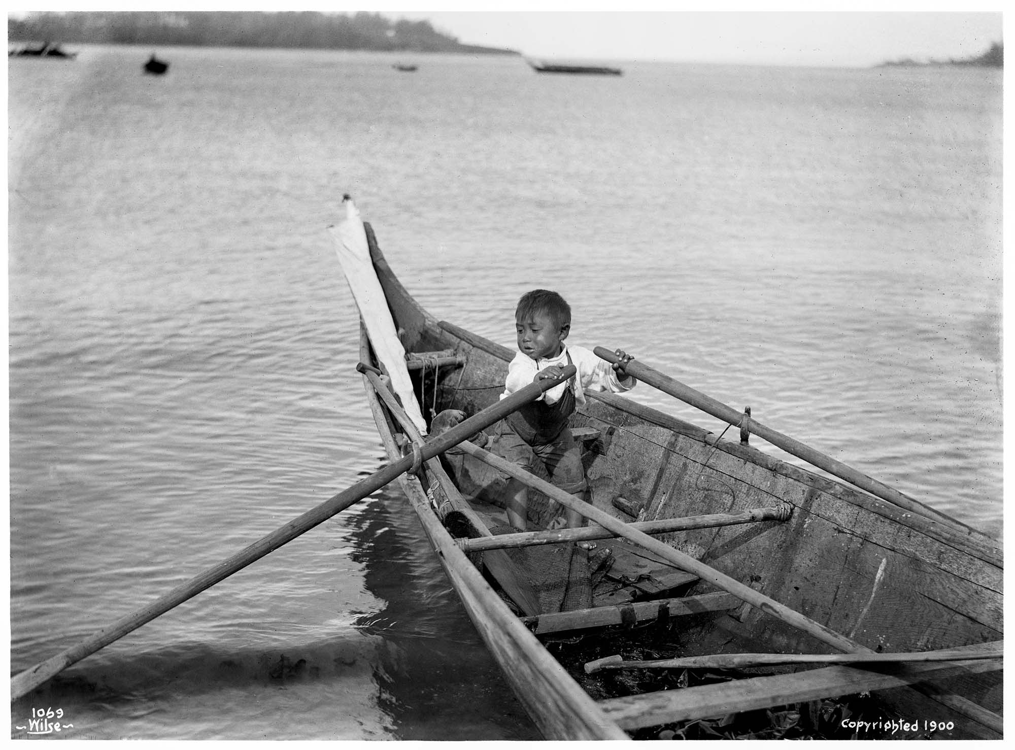 Image of Makah boy rowing a canoe at Neah Bay, 1900