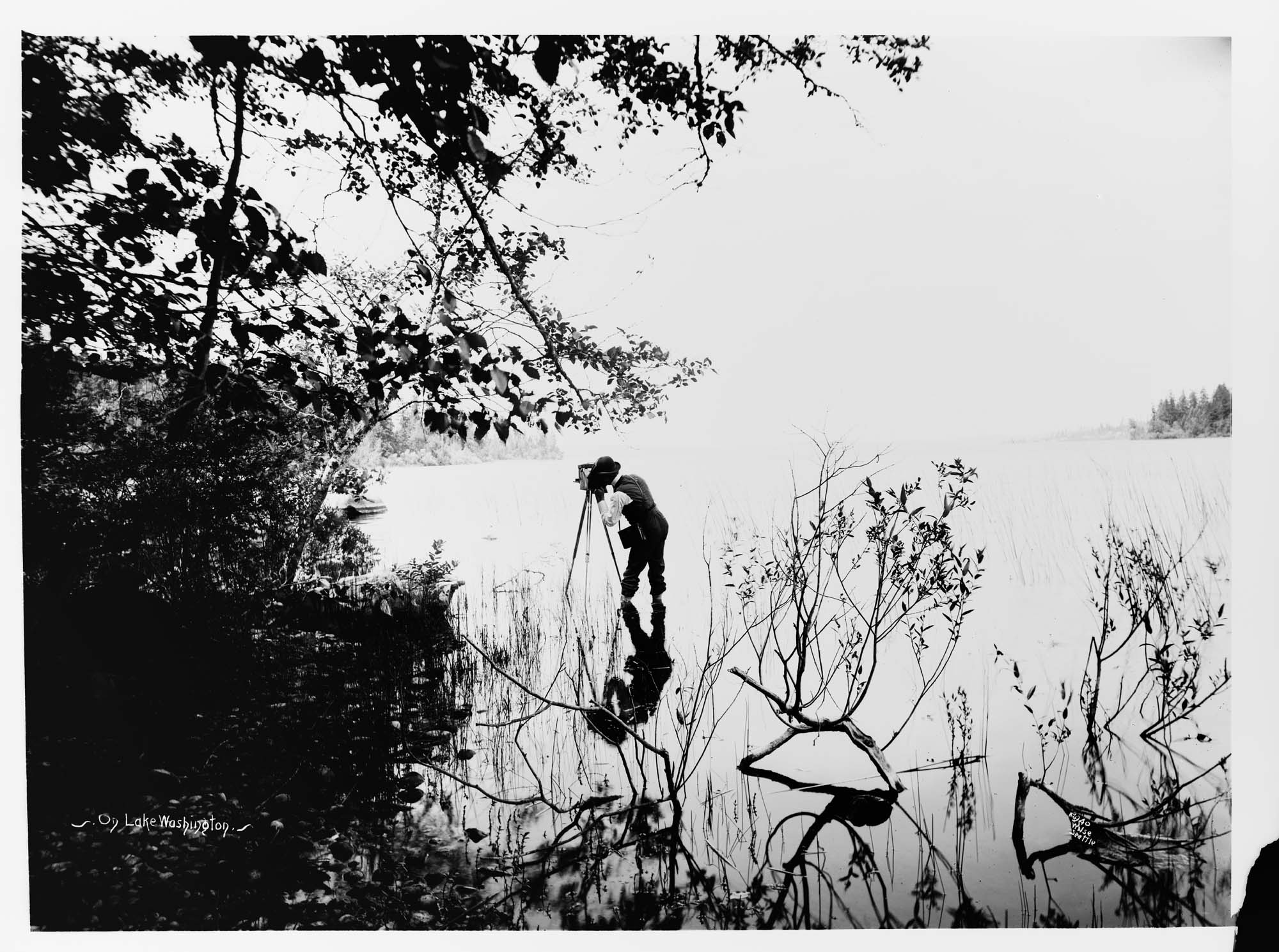 Image of Anders Wilse and camera in Lake Washington, circa 1900