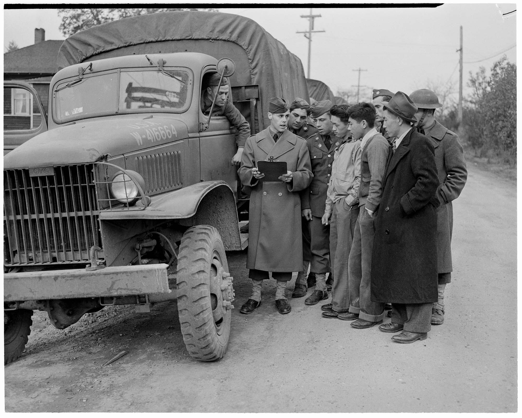Image of U. S. Soldiers and Japanese Americans standing by truck, March 25, 1942