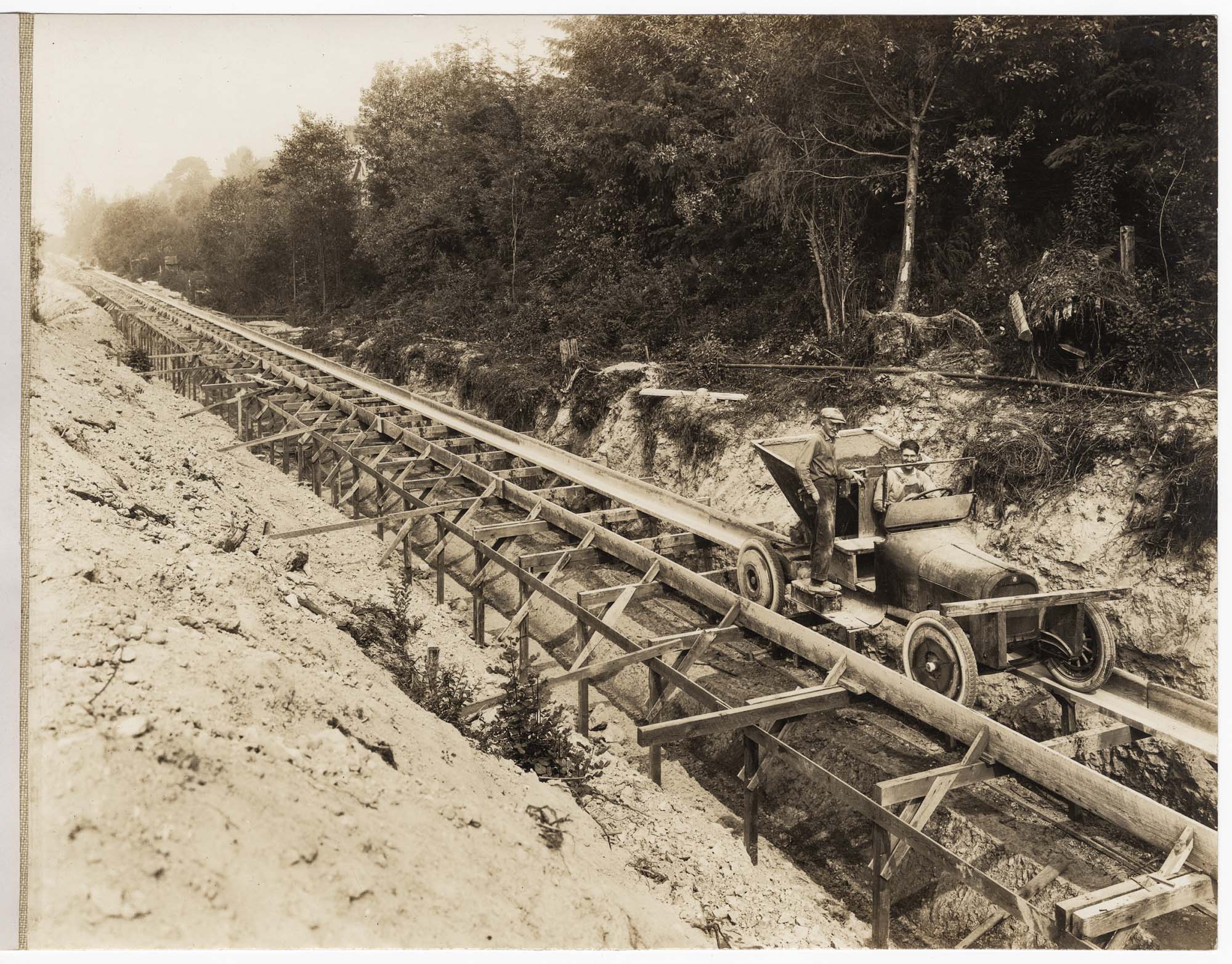 Image of Men in concrete transport car on tracks over sewer construction, circa 1925
