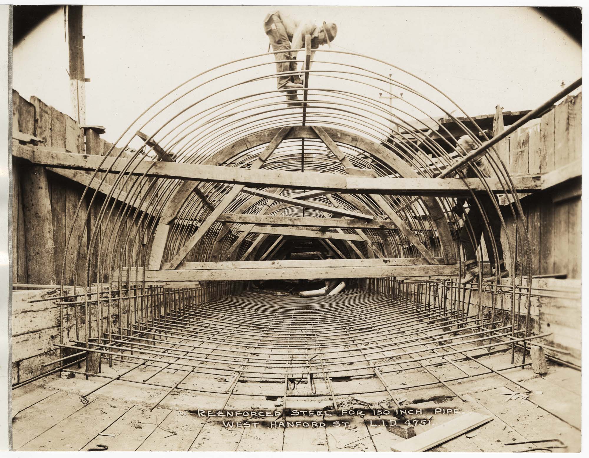 Image of Man working on reinforced steel cable pipe frame, circa 1929