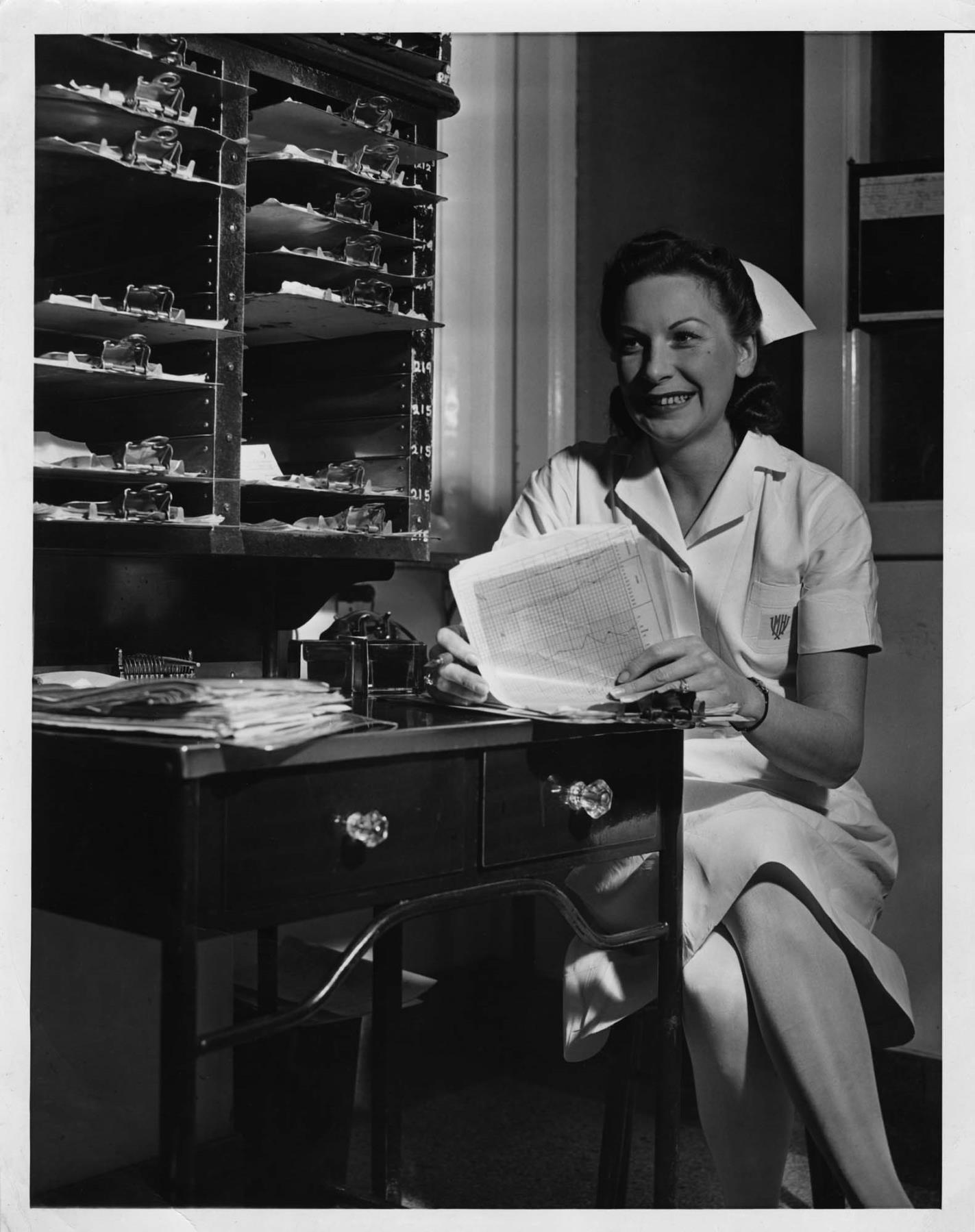 Image of Helene Madison in nurse's uniform seated at desk, circa 1936
