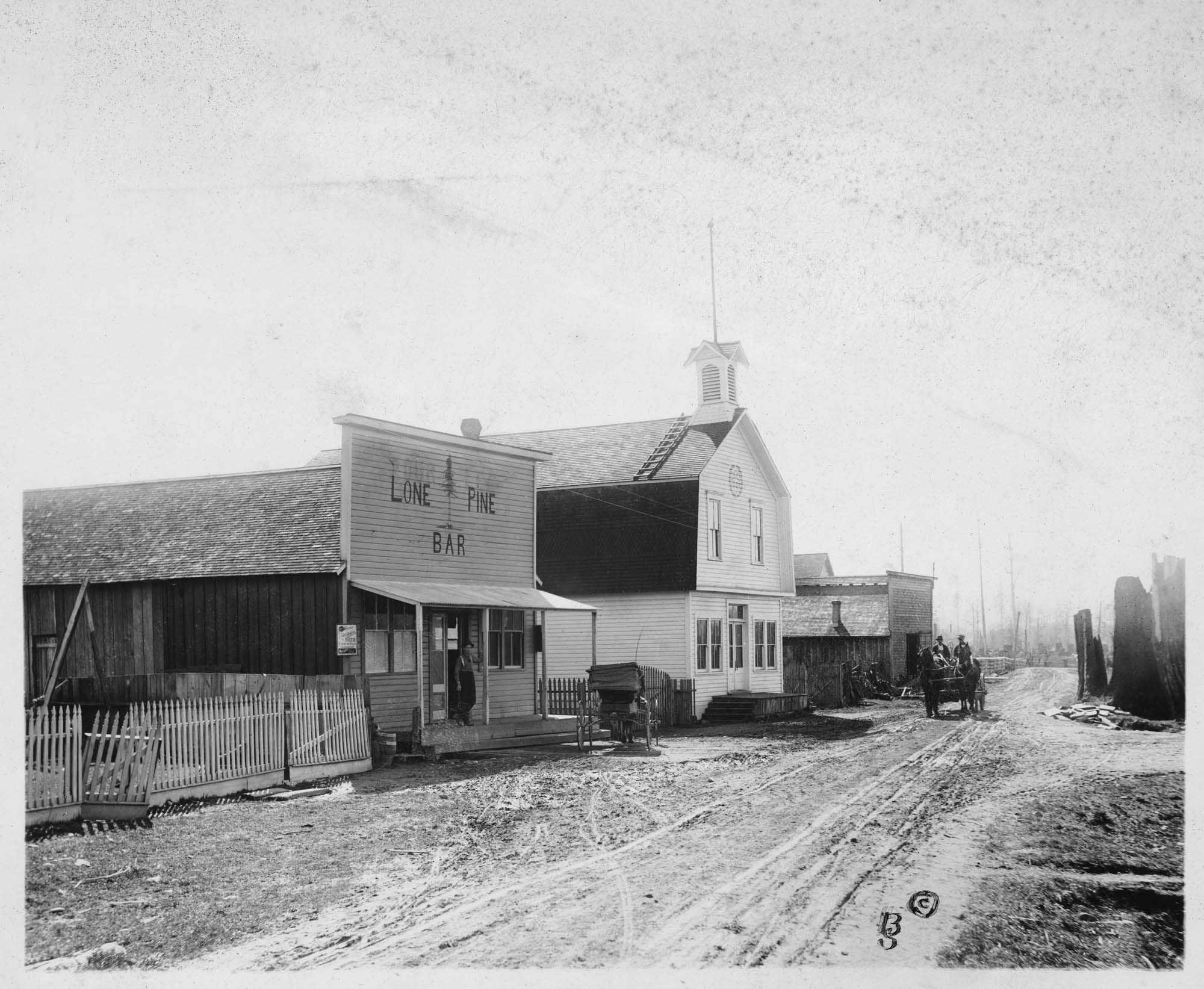 Image of Lone Pine Bar and Odd Fellows Hall on dirt road, probably Bainbridge Island, circa 1905
