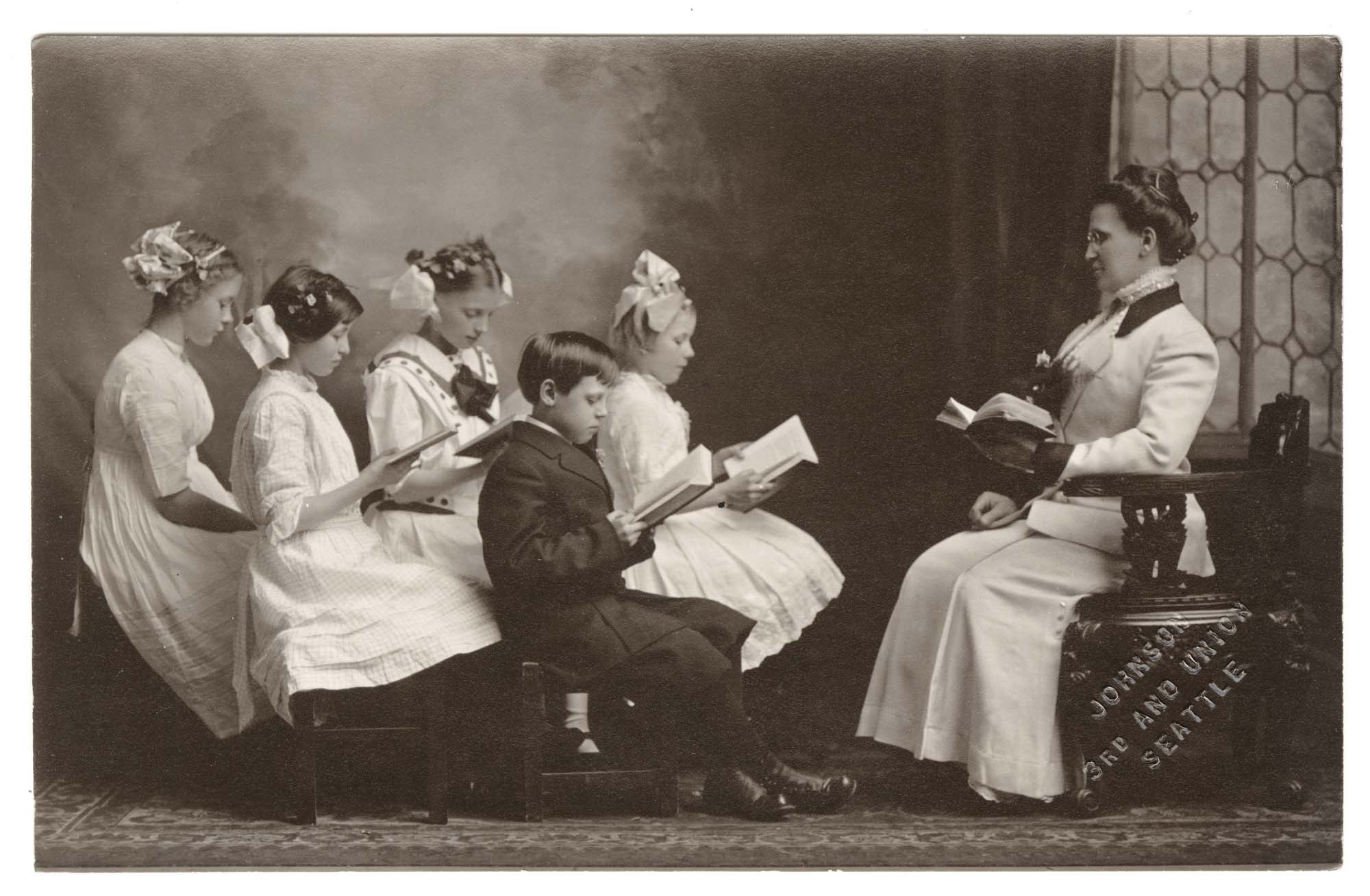Image of Anna Brand with son Leonard and other children reading a lesson, Seattle circa 1910