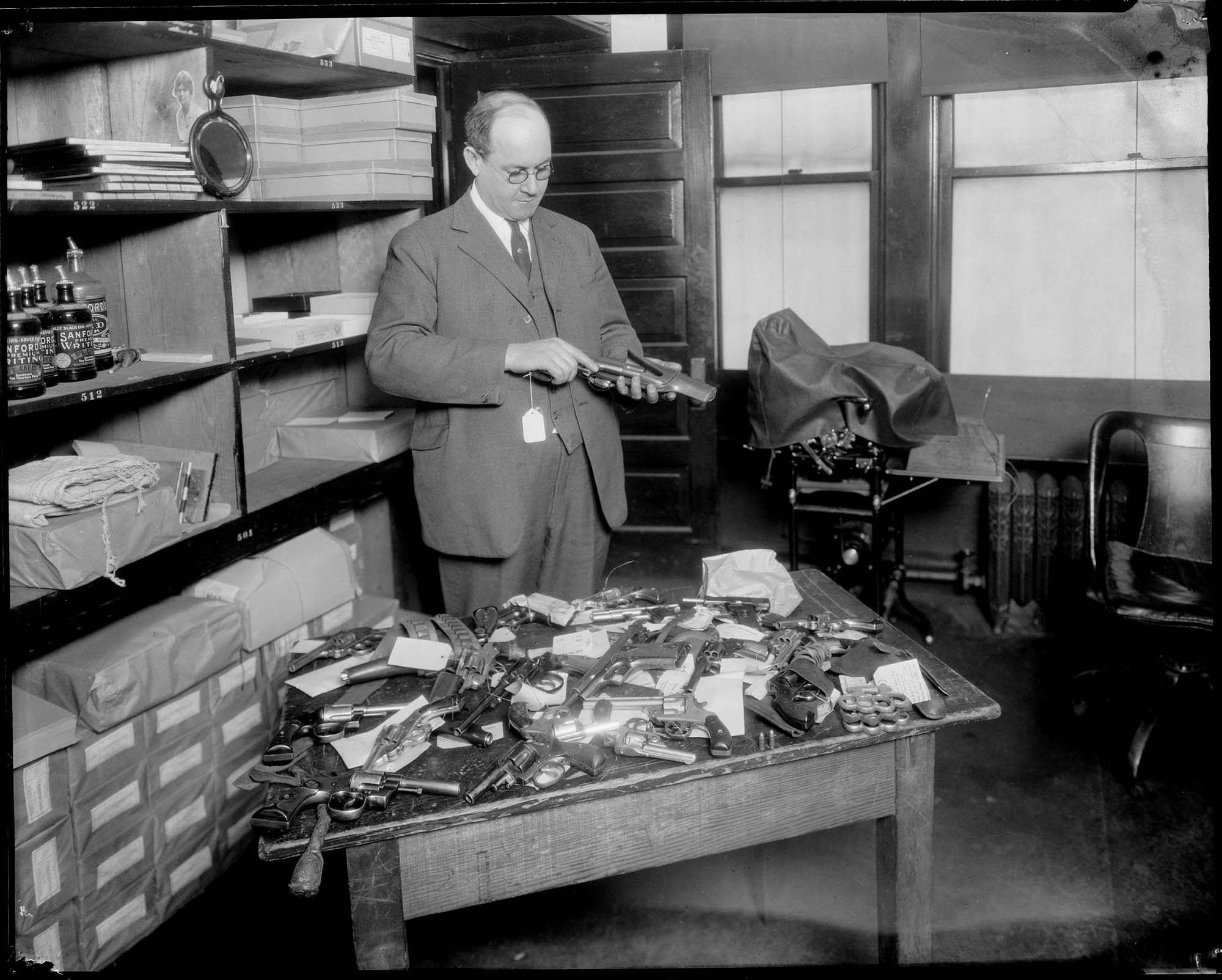 Image of Firearms and other weapons in the police department property room, circa 1922