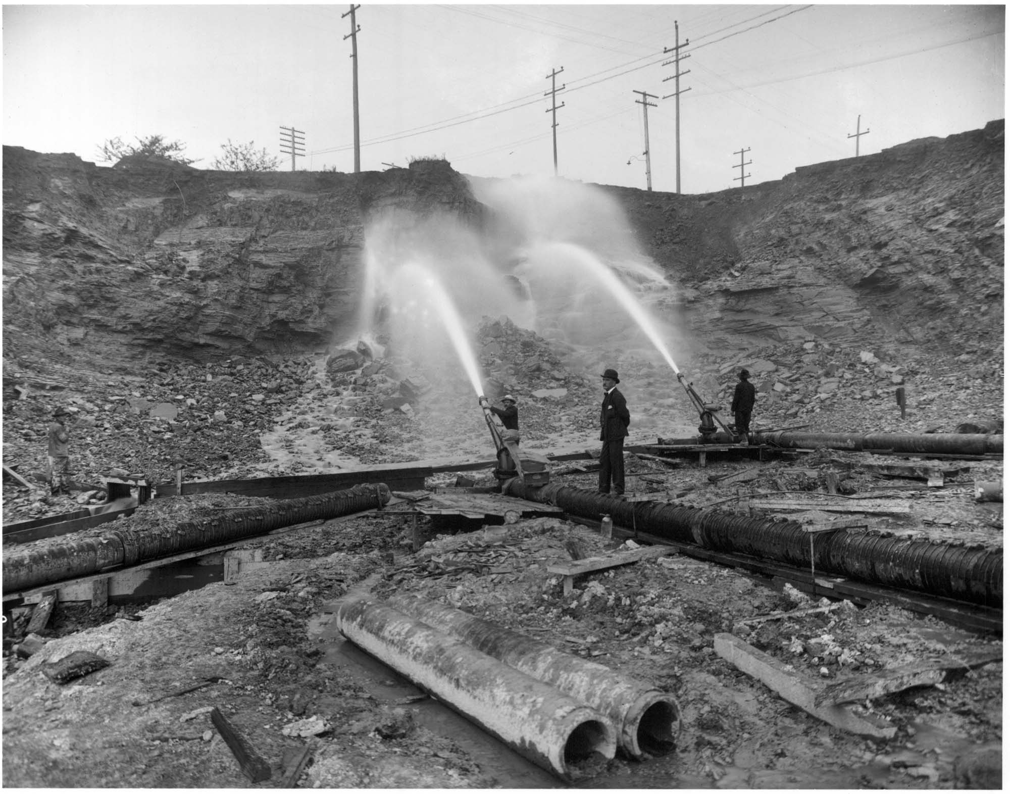 Image of Workers using water hoses to regrade Denny Hill, Seattle, circa 1909