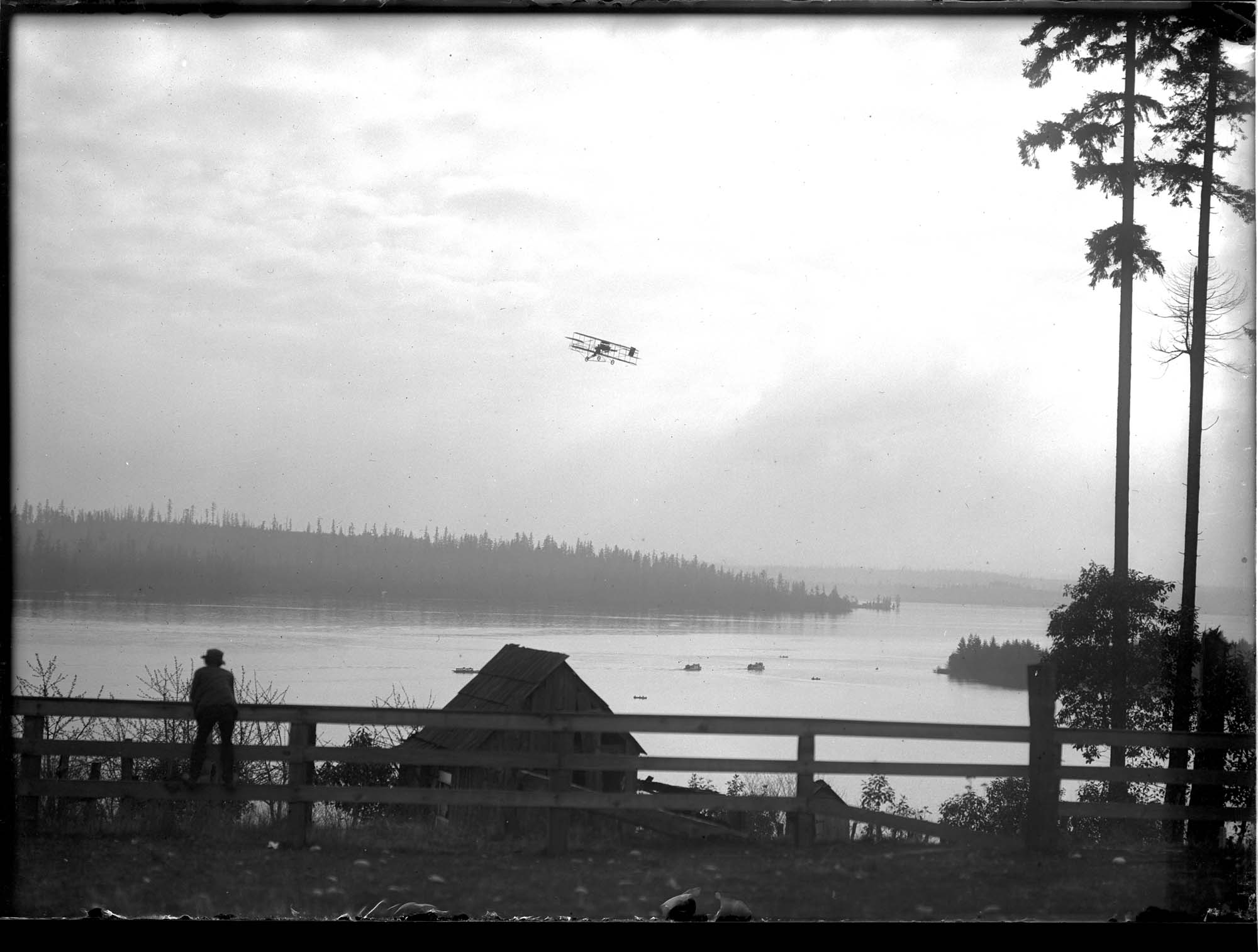 Image of Charles Hamilton's biplane over a lake, March 1910
