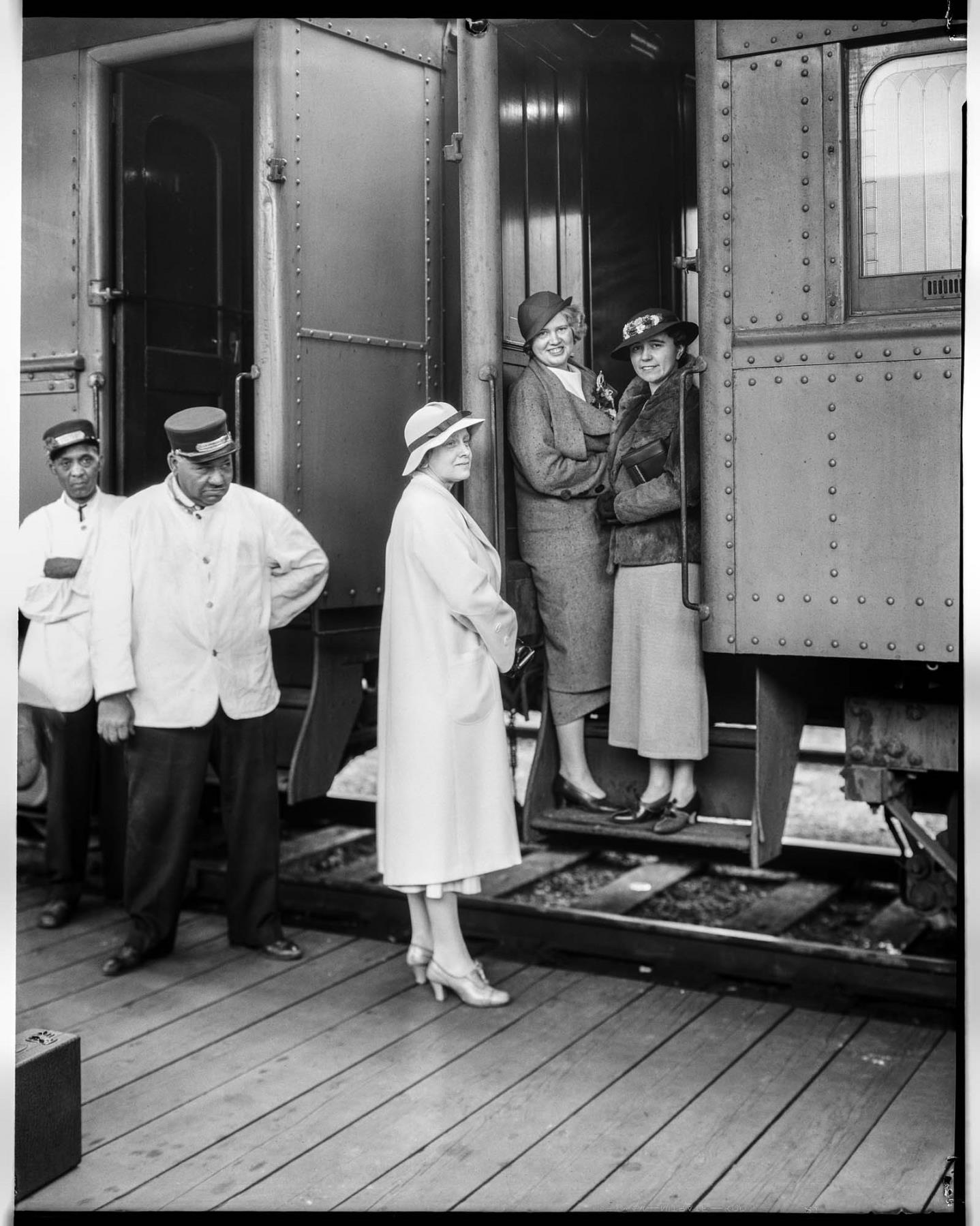 Image of Pullman porters and women on the railroad platform, May 26, 1934