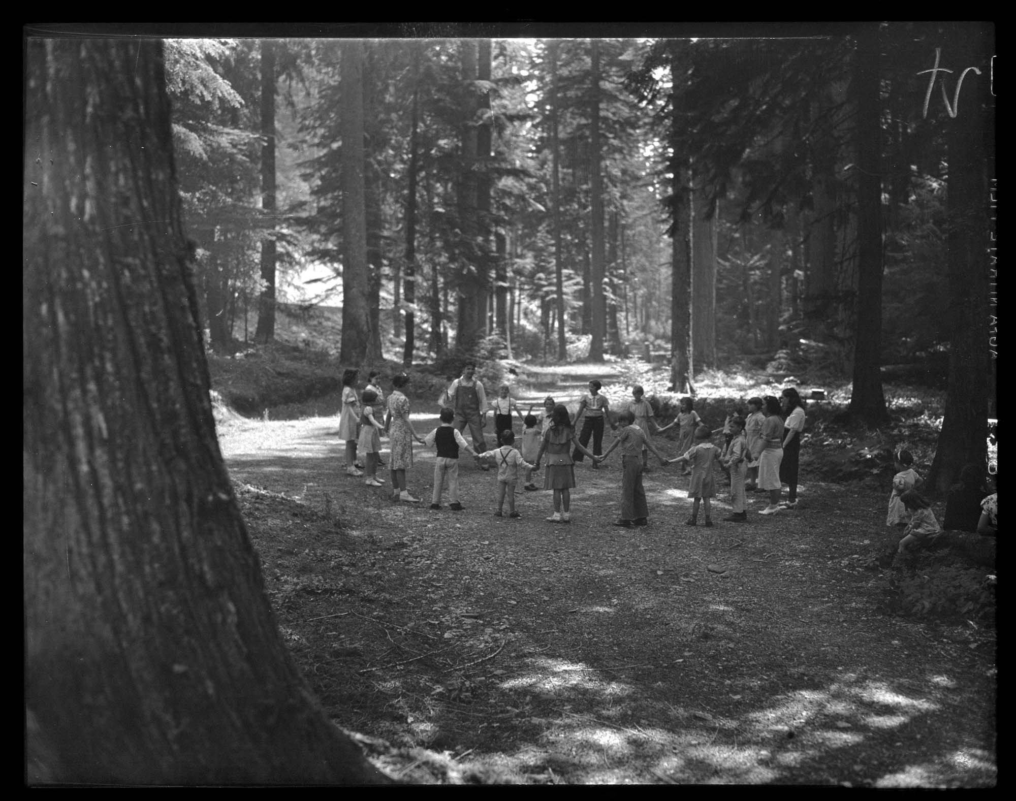 Image of Circle of children holding hands in a wooded clearing, 1939