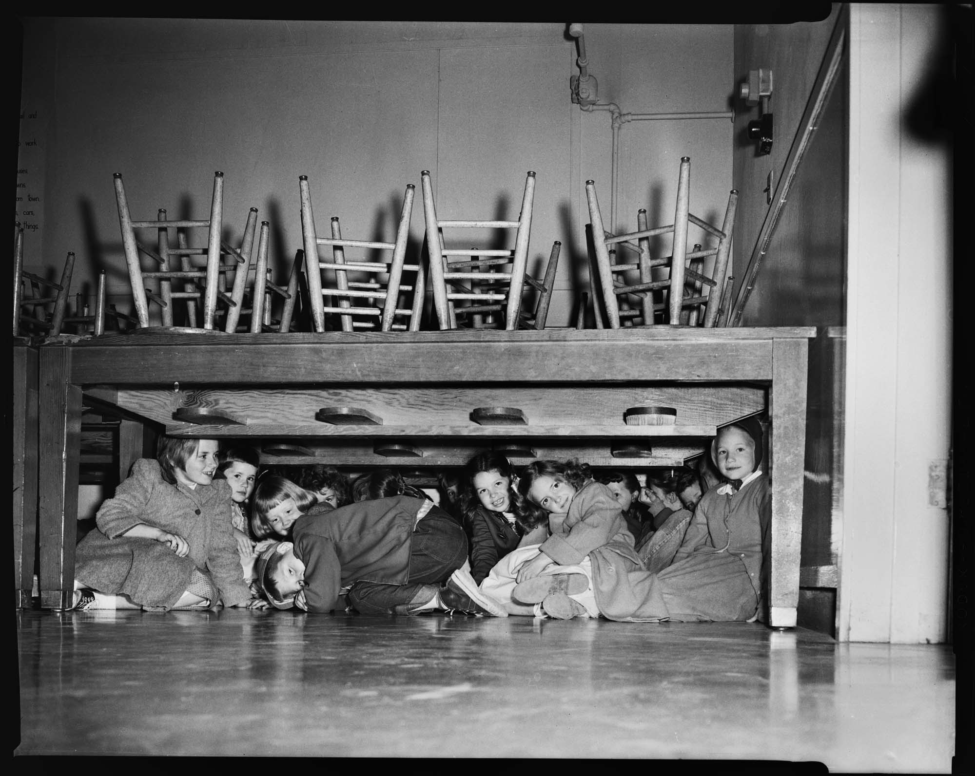 Image of Children under a table during an air raid drill, May 6, 1958