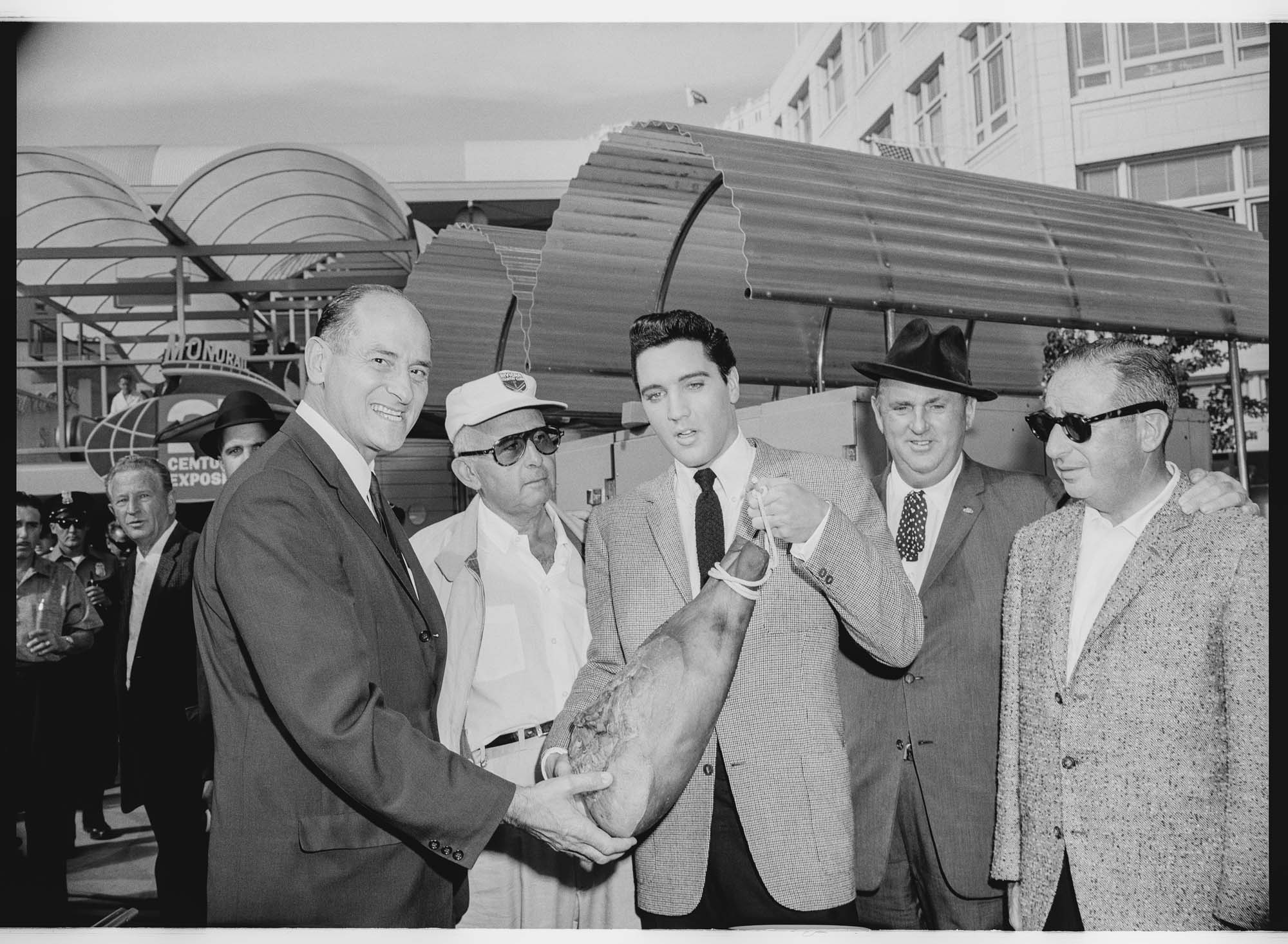 Image of Elvis Presley presenting a gift to Washington Governor Albert Rosellini, Monorail Station, Westlake Avenue, Seattle, September 5, 1962