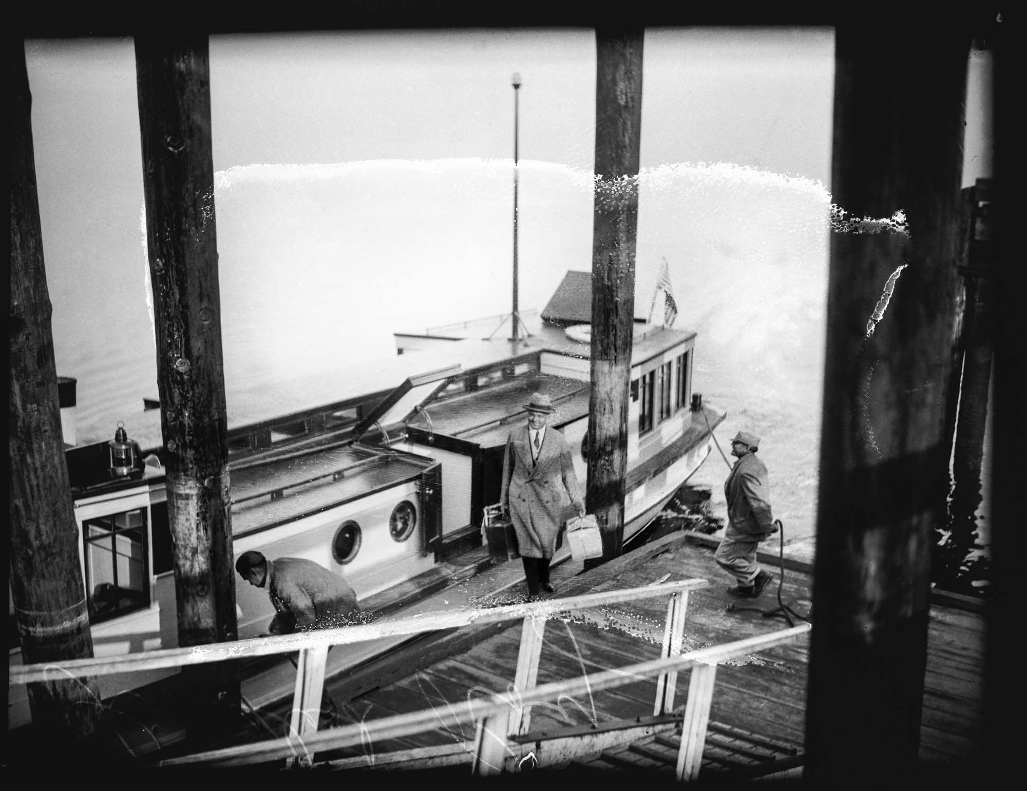 Image of Roy Olmstead in a boat arriving at a dock, Steilacoom, 1931