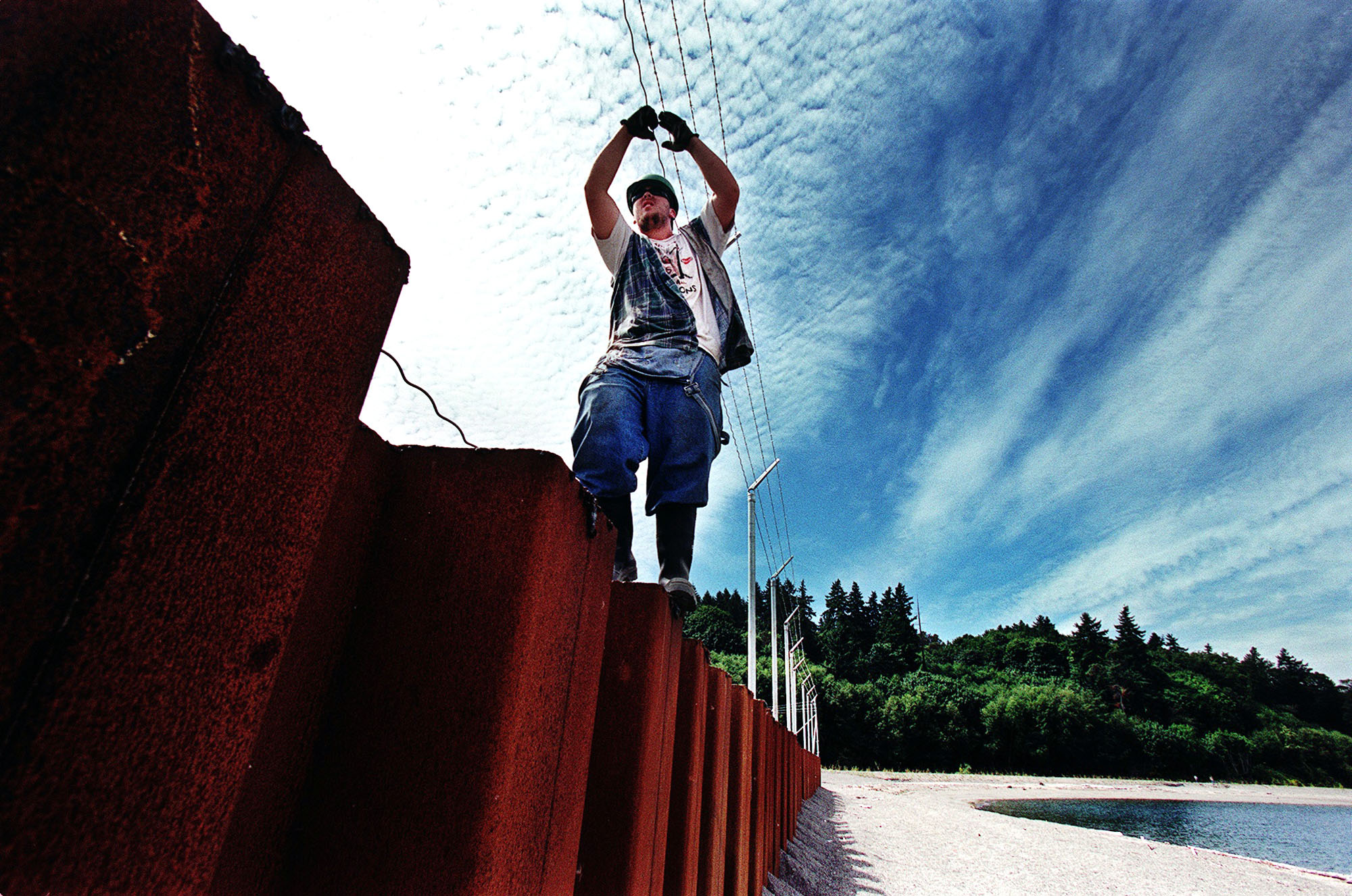 Image of Worker installing barbed wire on wall in Eagle Harbor, Bainbridge Island, November 9, 2002