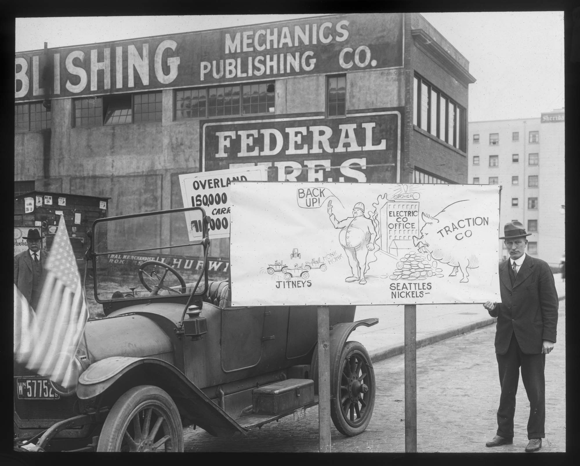 Image of Jitney bus driver with sign criticizing streetcar system, Seattle, 1918