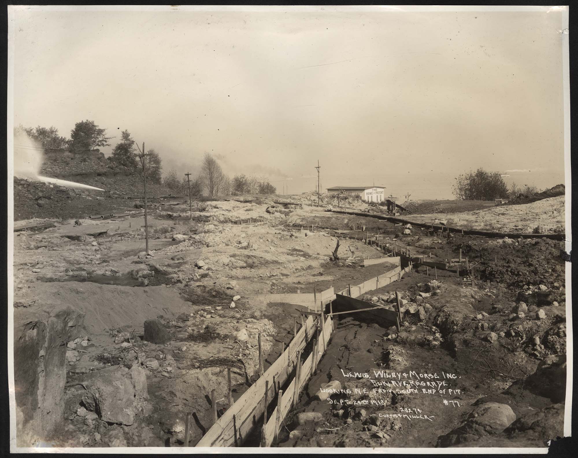 Image of Alki Avenue regrade showing water cannon, with flour mill in distance, September 24, 1913