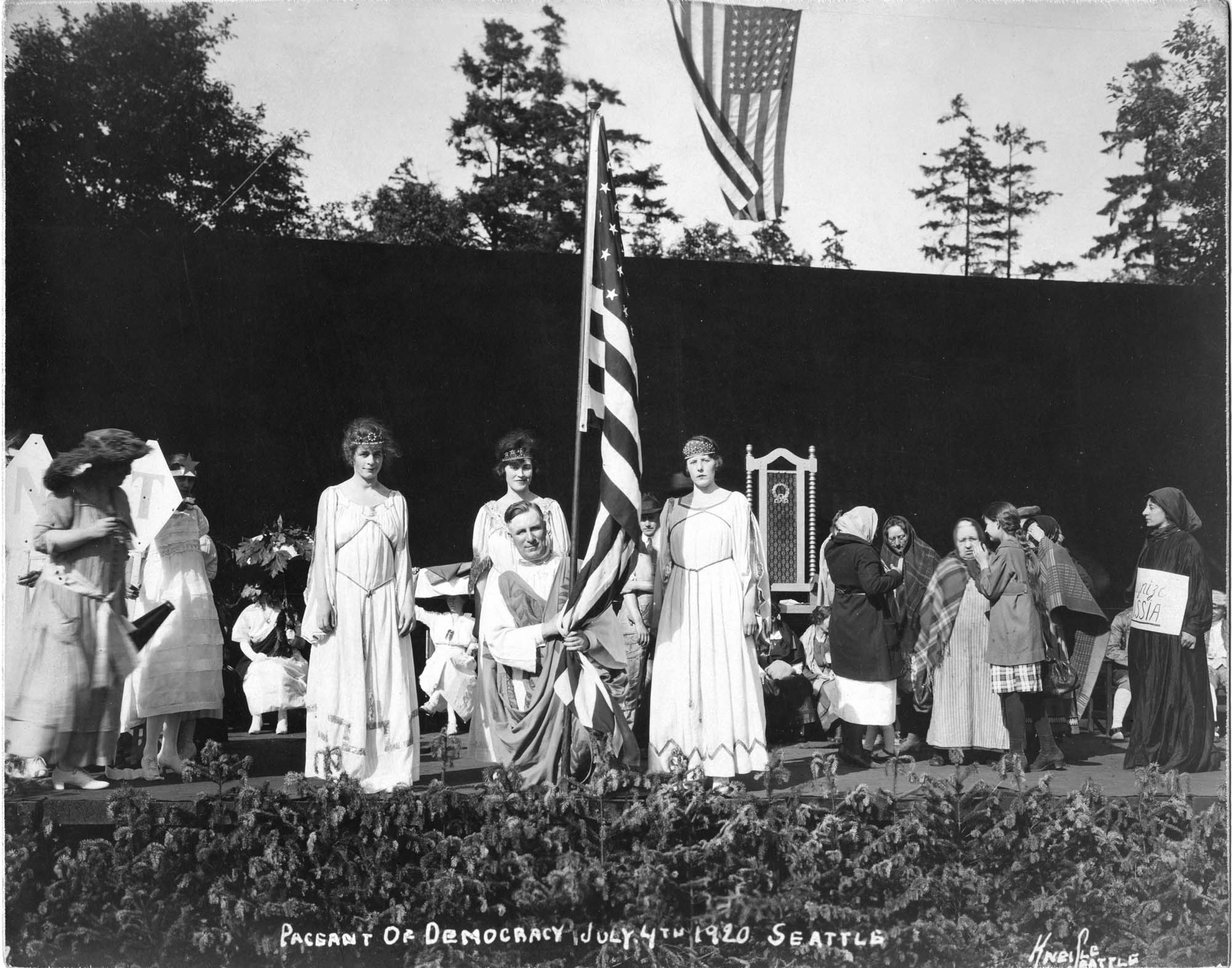 Image of Man in ancient Greek dress holding American flag at the 