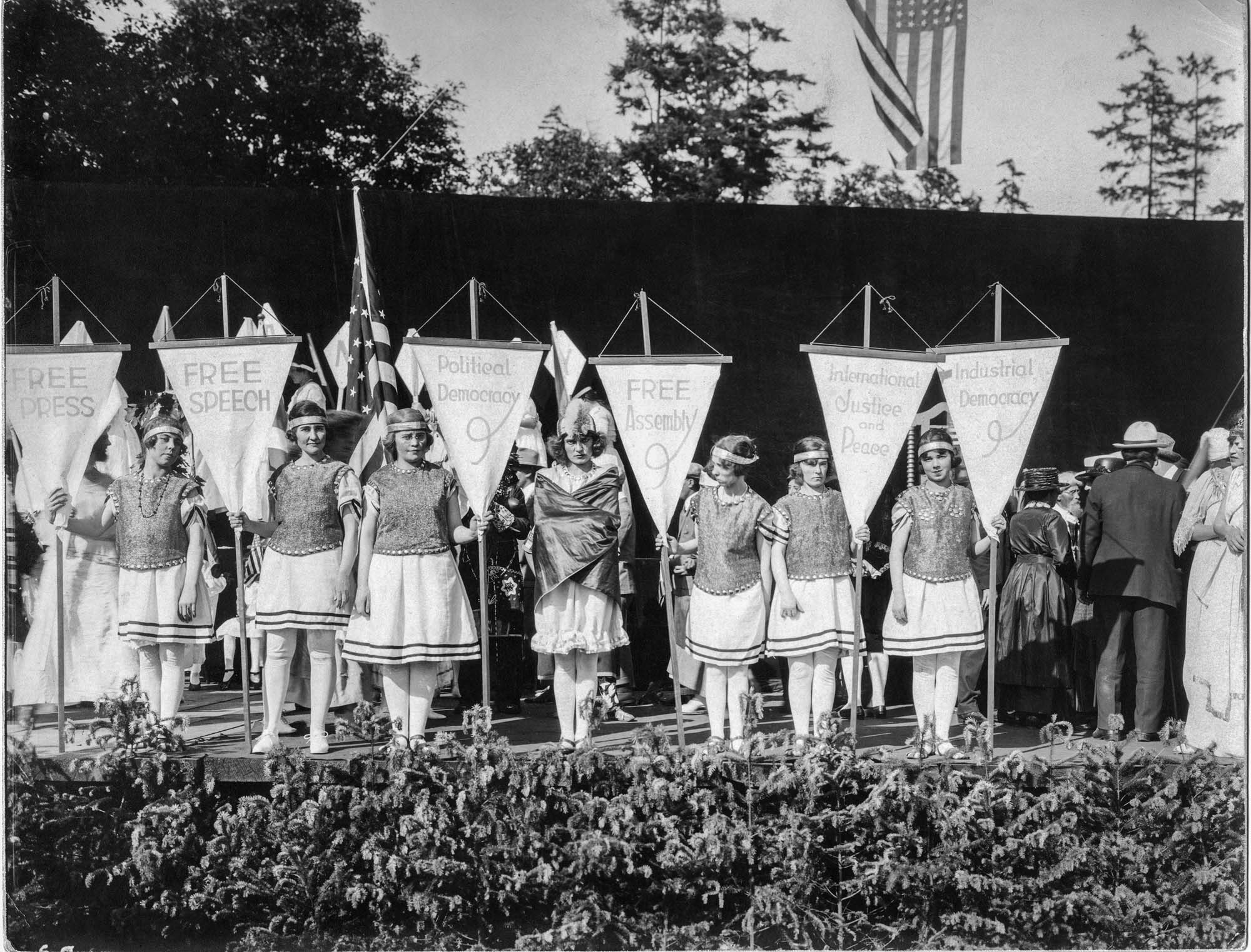Image of Young women in costume holding banners at the 