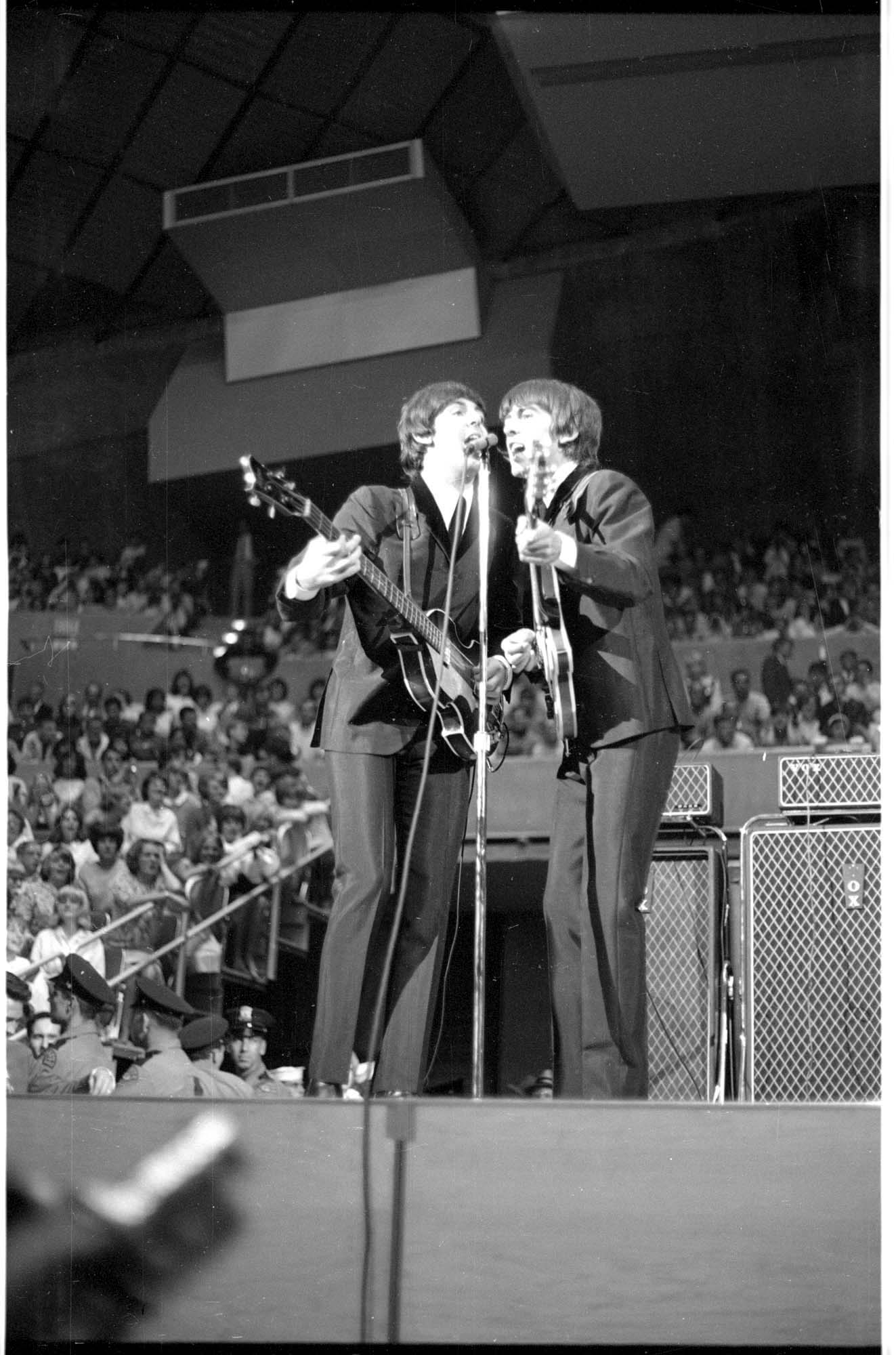 Image of Paul McCartney and George Harrison singing during the Beatles concert at Seattle Center Coliseum, August 21, 1964