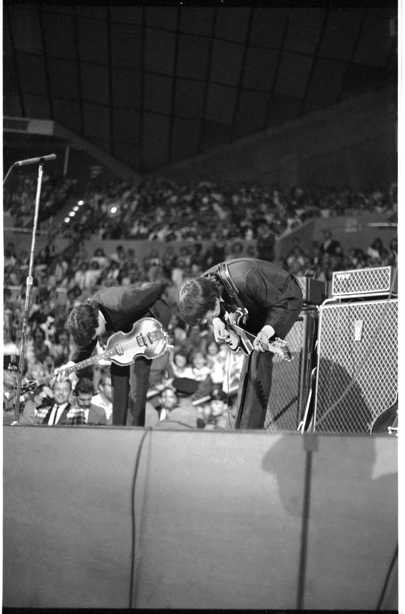 Image of Paul McCartney and George Harrison taking a bow at the Beatles concert in Seattle Center Coliseum, August 21, 1964