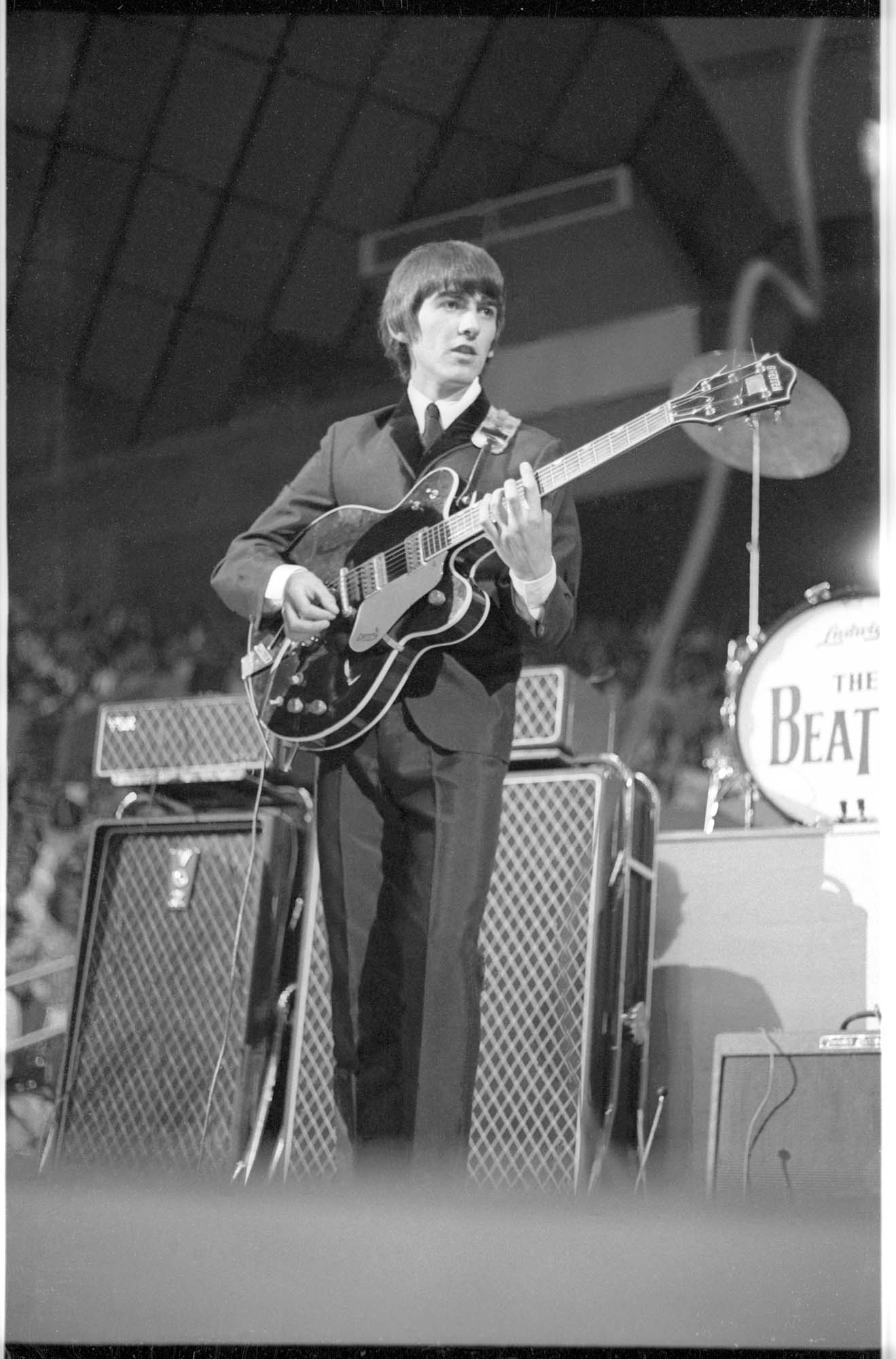 Image of George Harrison playing guitar at the Beatles concert, Seattle Center Coliseum, August 21, 1964