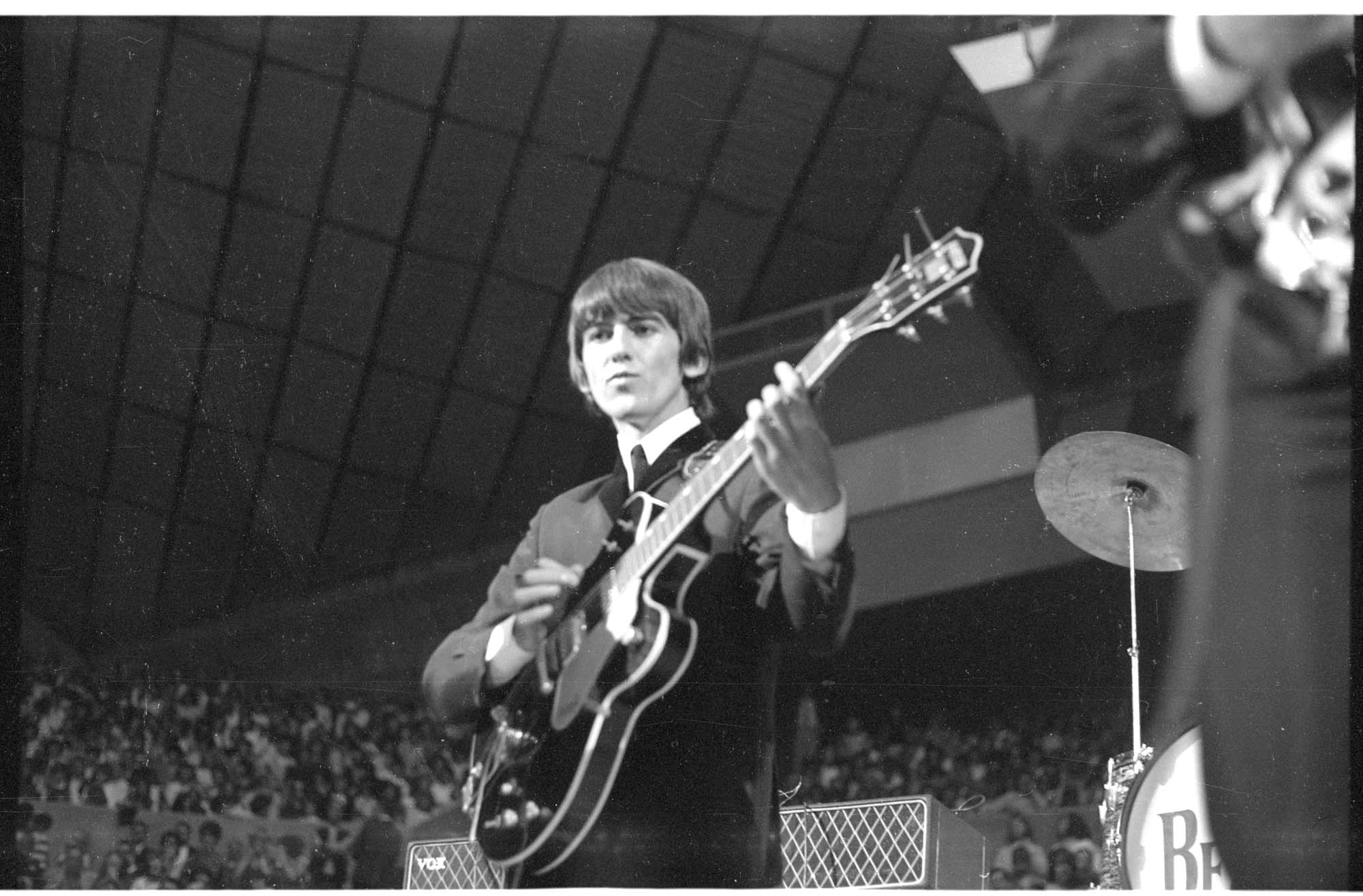 Image of George Harrison playing guitar at the Beatles concert at Seattle Center Coliseum, August 21, 1964