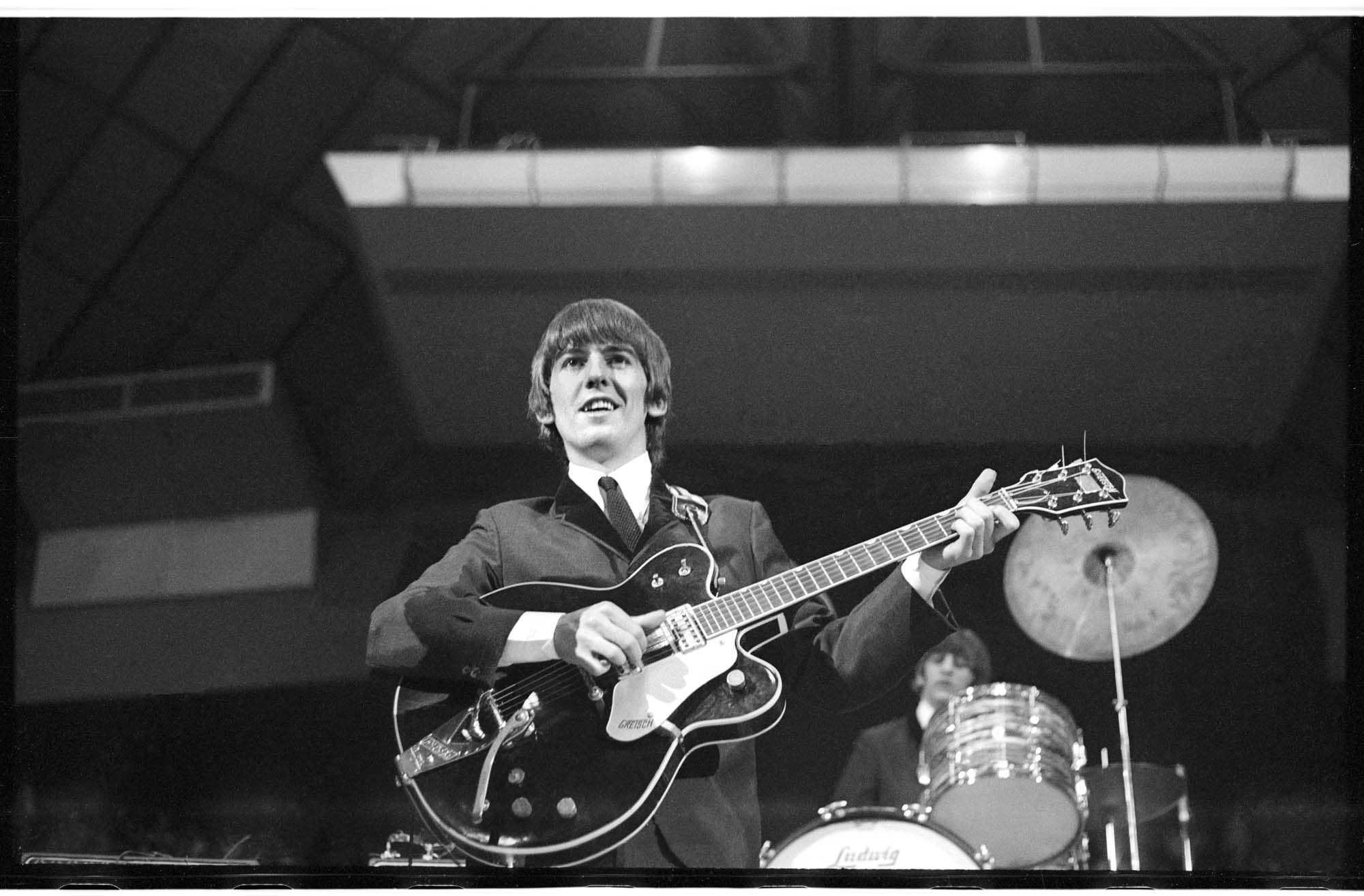 Image of George Harrison playing guitar at the Beatles concert, Seattle Center Coliseum, August 21, 1964