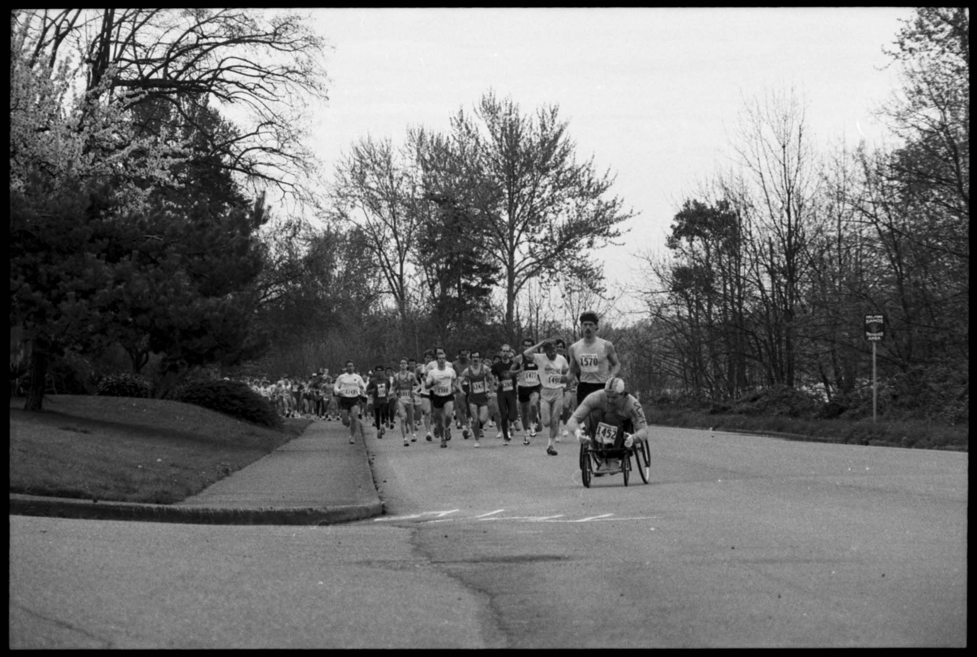 Image of Runners and wheelchair racer in 10K race, probably in Seattle, July 1, 1986