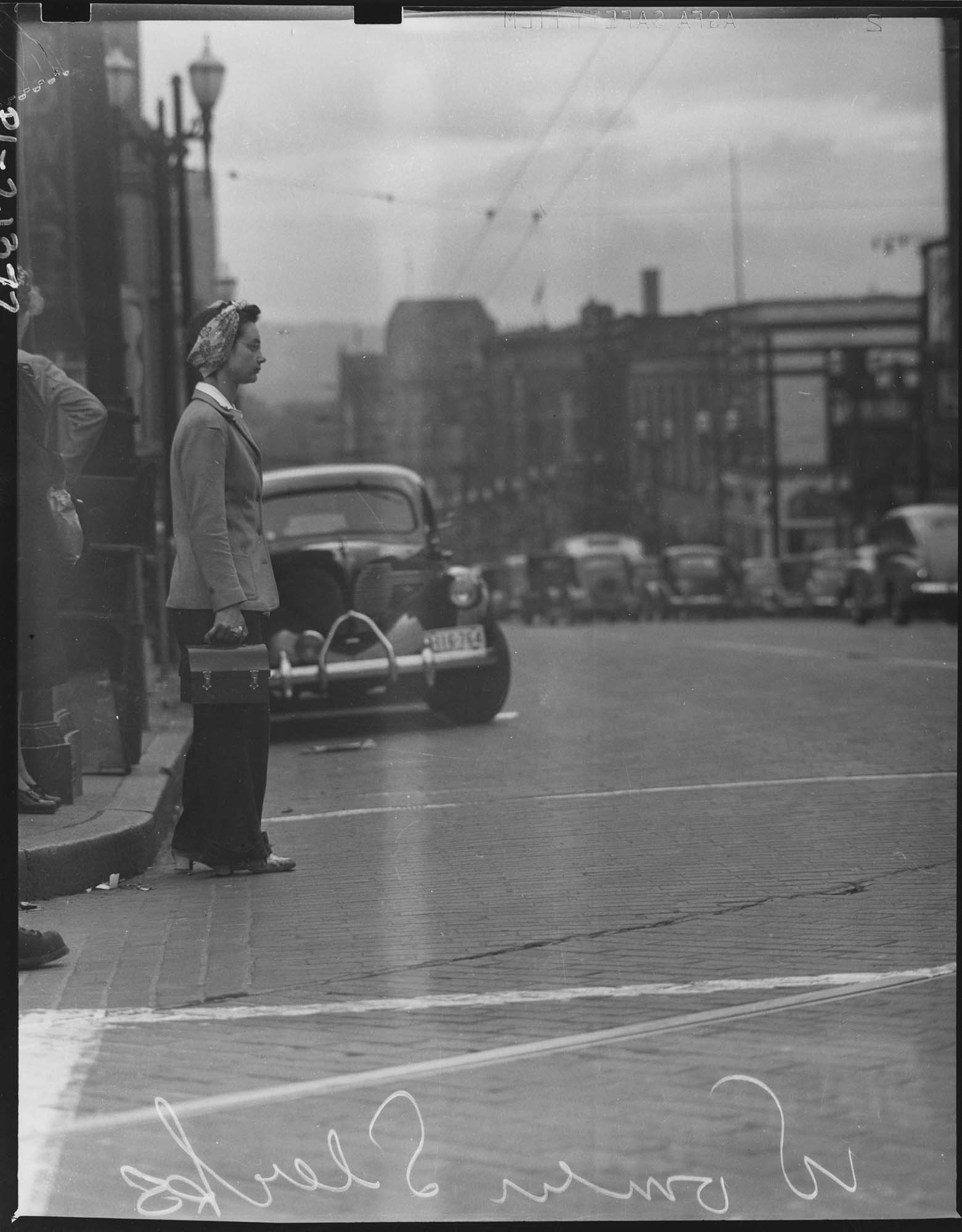Image of Woman in work clothes waiting to cross street, Seattle, 1942
