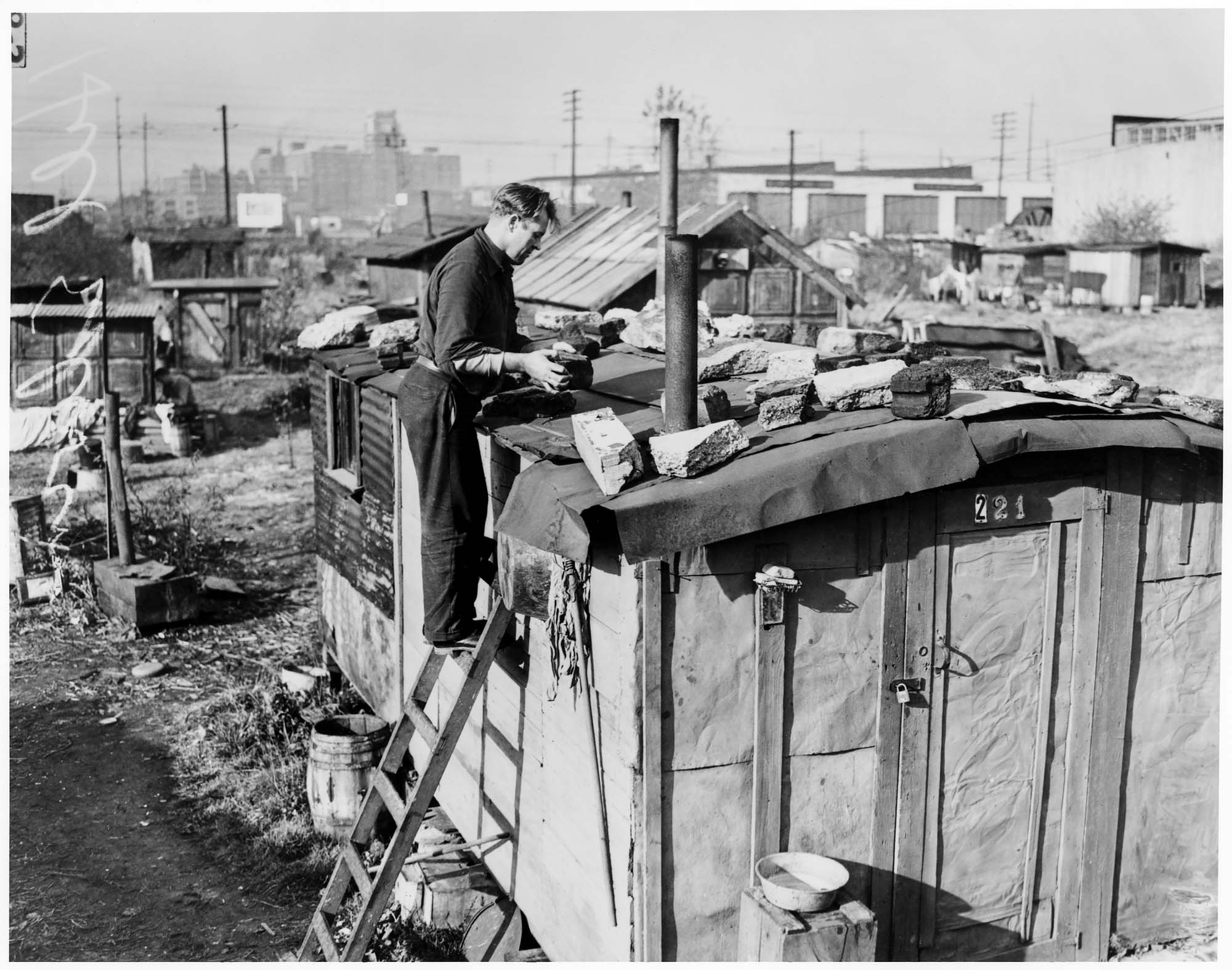 Image of Edwin Hill repairing roof of shack in Hooverville, Seattle, November 1939