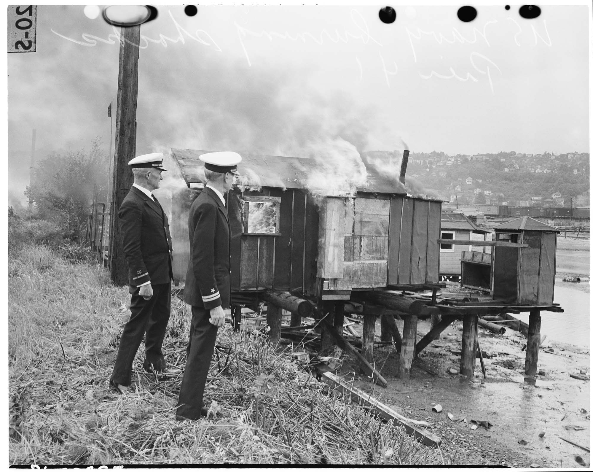 Image of Naval officers watching Hooverville shack burn, June 6, 1942