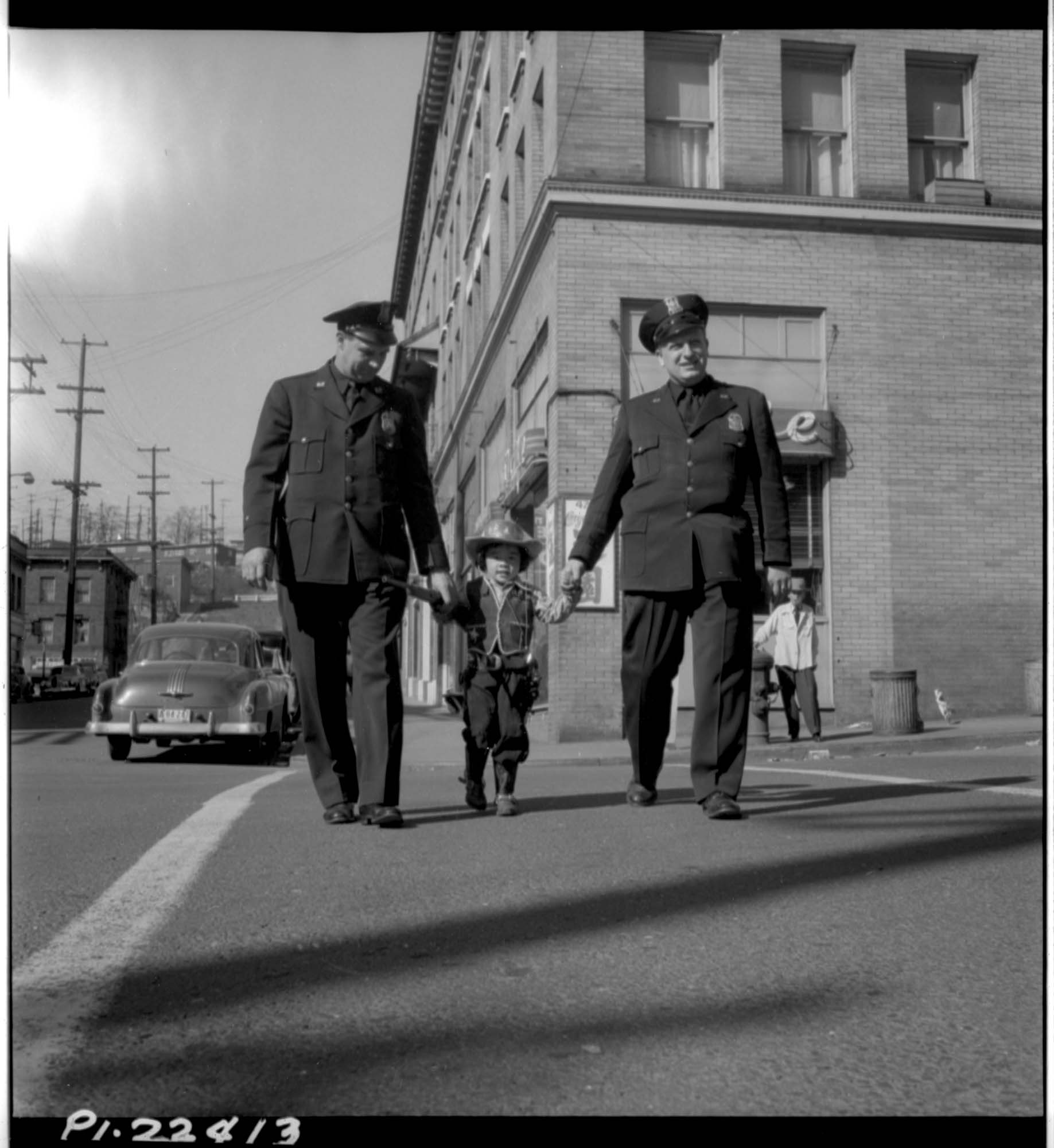 Image of Cheryl Chow in cowboy suit walking with policemen, April 1951