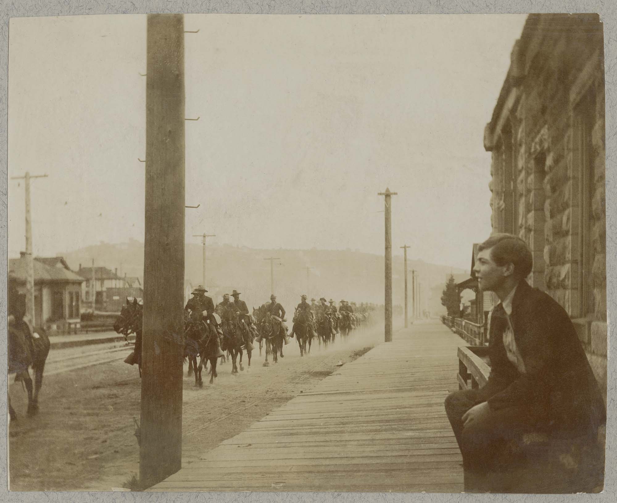 Image of Boy watching cavalry ride past Second and Pine, Seattle, August 7, 1900