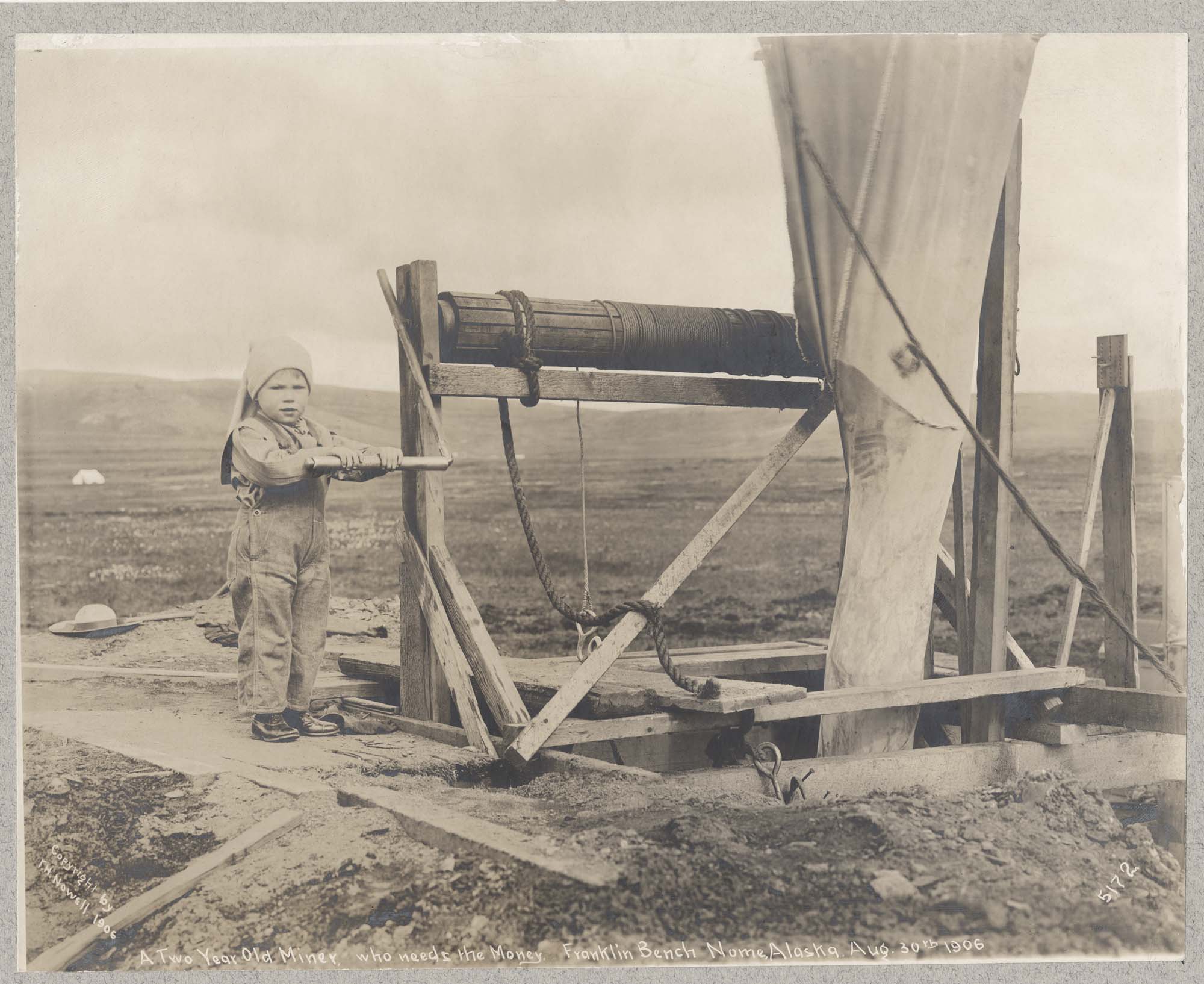 Image of Child near mining equipment, Nome, August 30, 1906