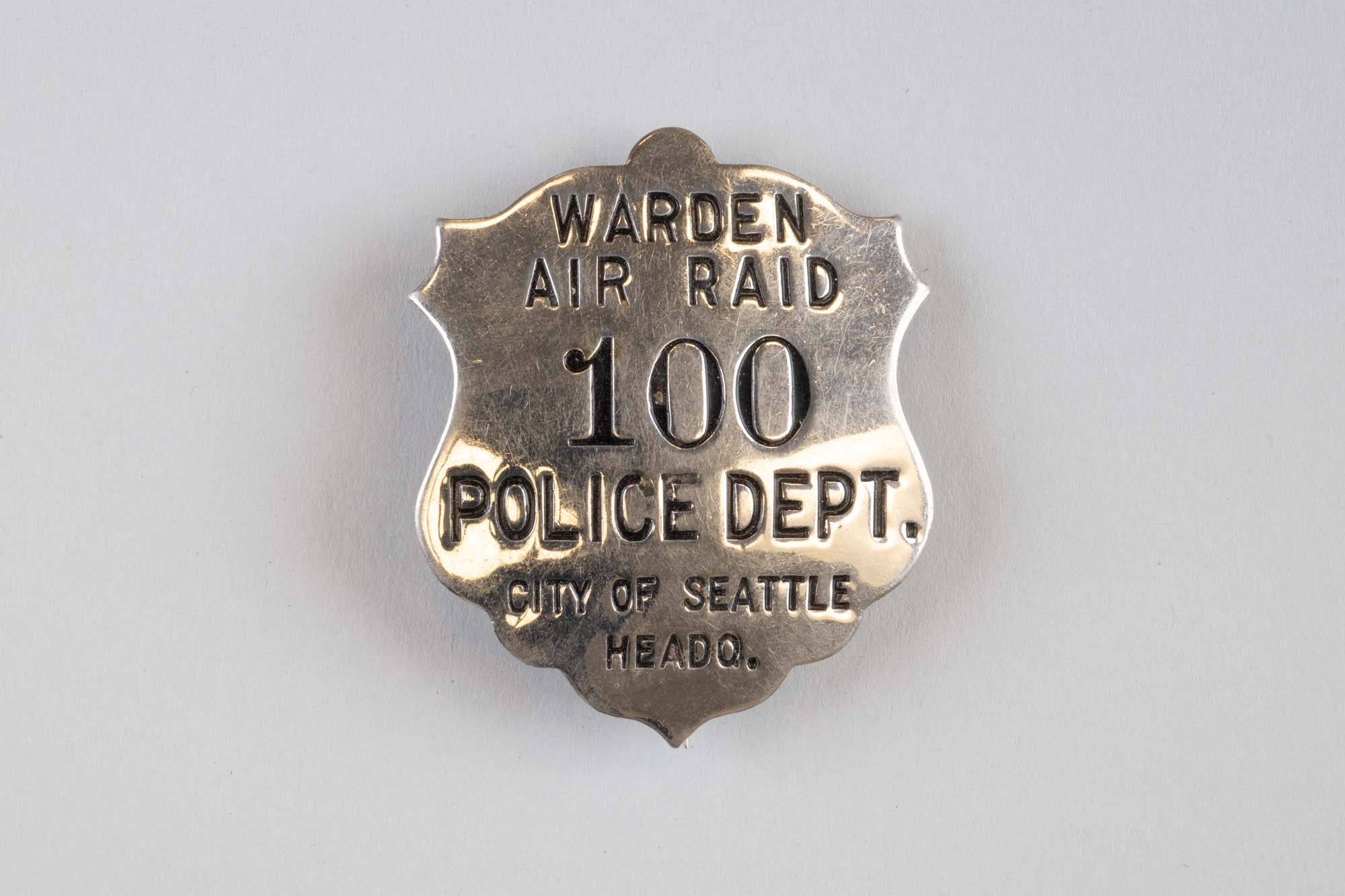 Image of Air Raid Warden's badge #100, Police Department, City of Seattle, ca. 1940