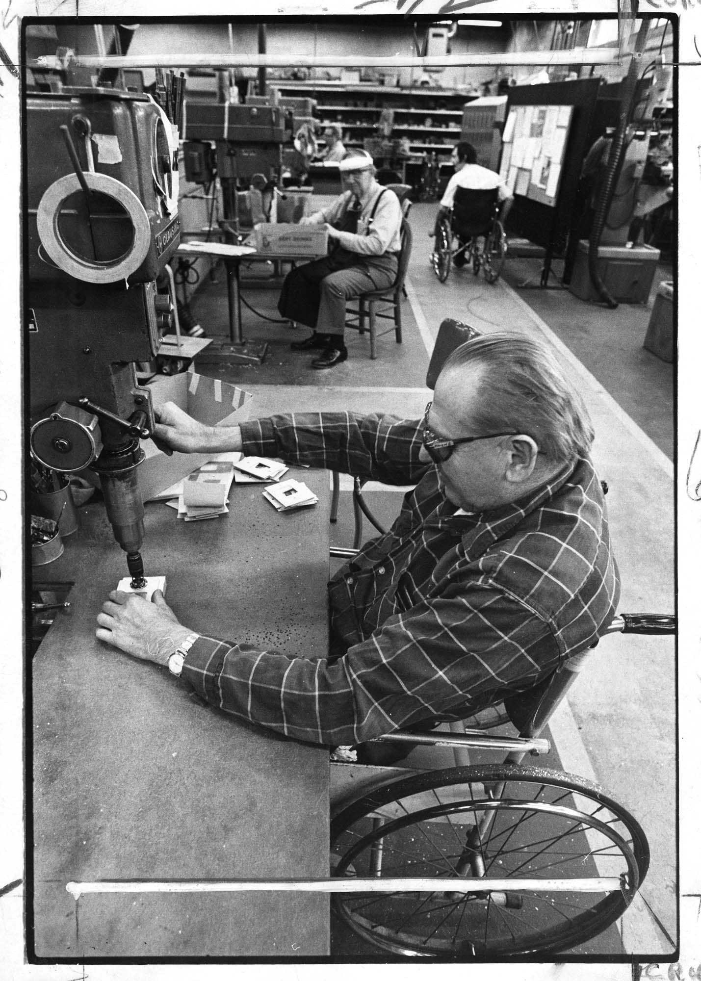 Image of Paul Koyne at a drill press making parts for Boeing at the United Cerebral Palsy machine shop, Seattle, October 1975