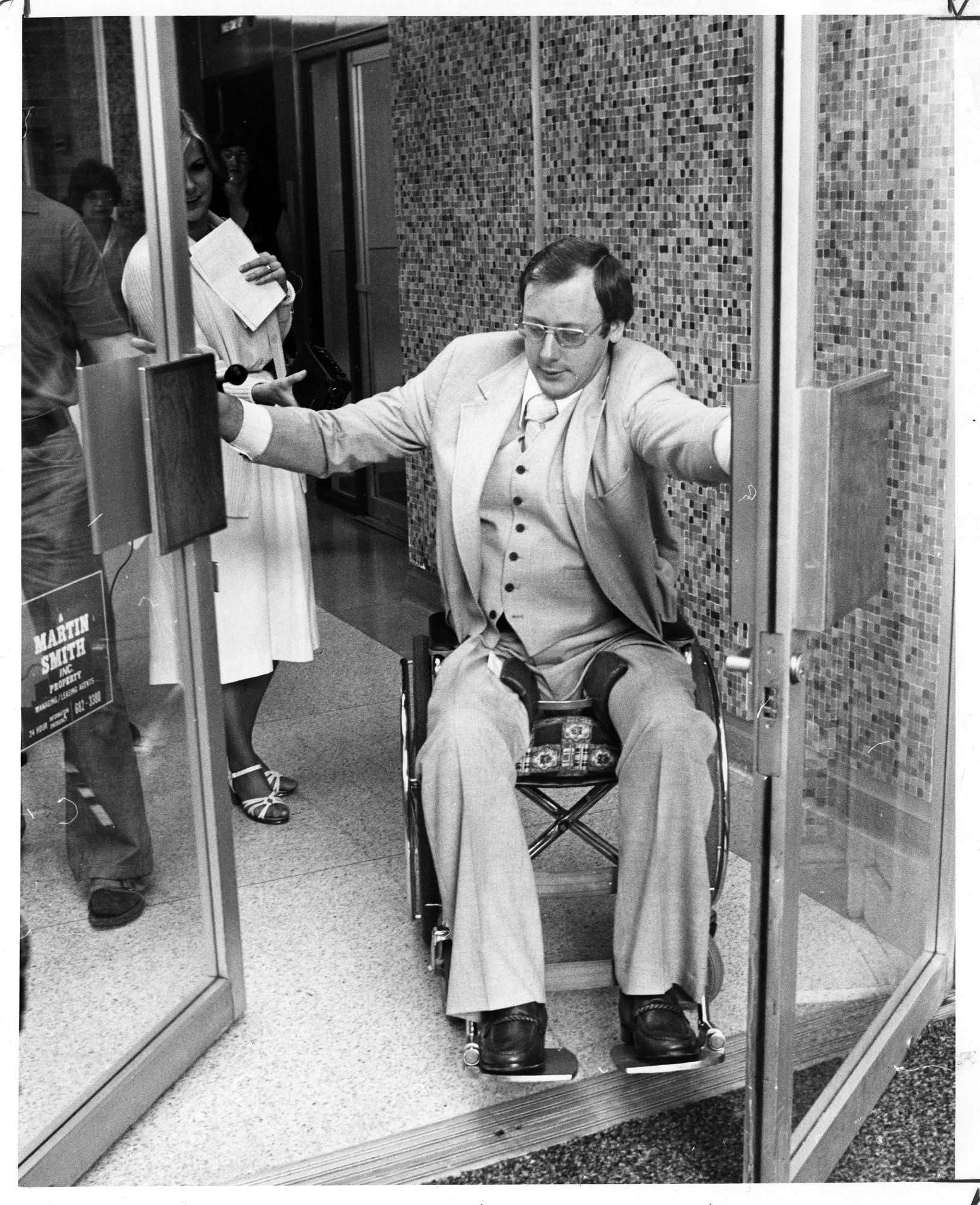 Image of Wheelchair user Mike Kovell using swinging doors, Seattle, July 1978