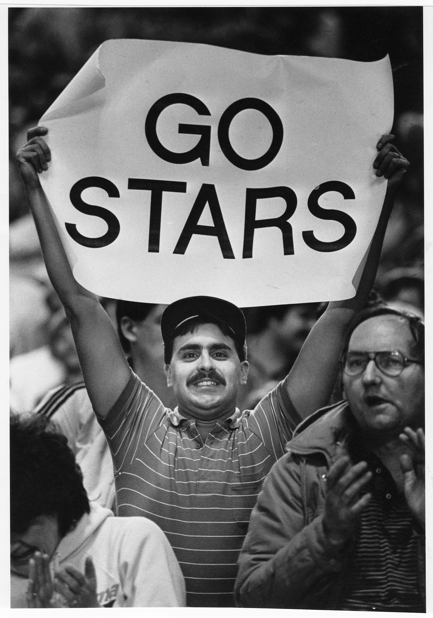 Image of Fan Wane Dallasto holding banner supporting Tacoma Stars soccer team during playoff game at the Tacoma Dome, April 16, 1986
