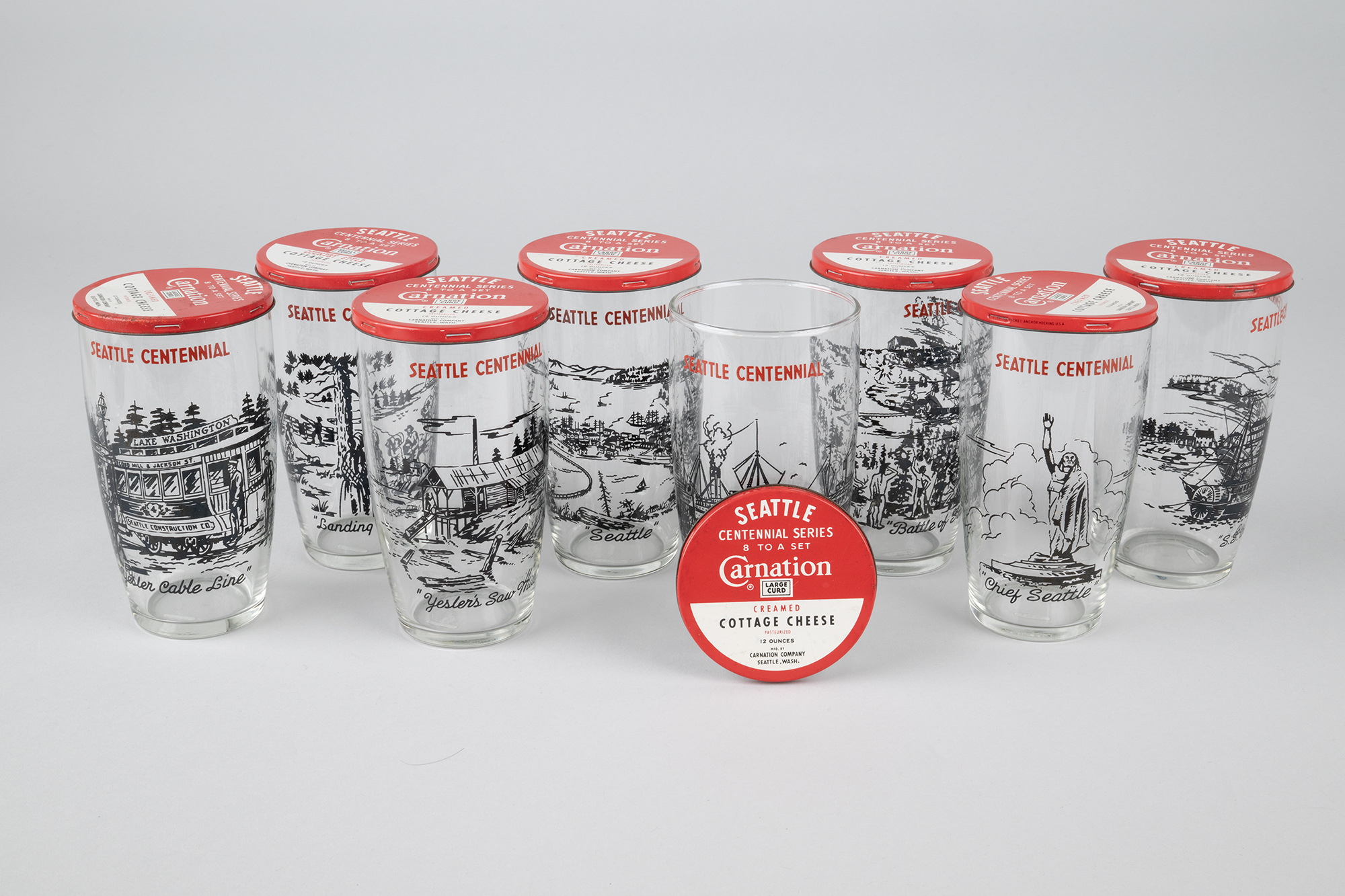 Image of Set of eight Seattle Centennial glasses with Carnation Cottage Cheese tin lids, 1952