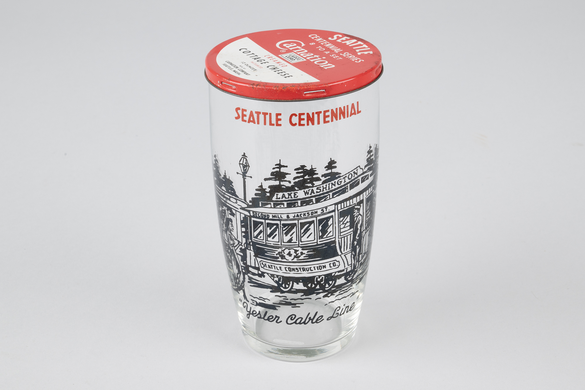 Image of Set of eight Seattle Centennial glasses with Carnation Cottage Cheese tin lids, 1952