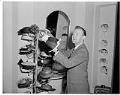 Image of John Eaton adjusting hats on display, Seattle, circa 1960