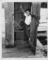 Image of Boy in outhouse, with tiny fish, circa 1956
