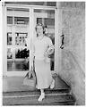 Image of Nancy Ramey leaving building with travel bag, Seattle, October 1956