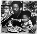 Image of Fred Brown holding son Terik during lunch at home, Seattle, July 1979