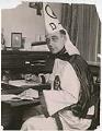Image of Luther Powell sitting at desk in Klan robes, circa 1923