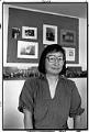 Image of Chizuko Omori at home in front of incarceration camp photos, Seattle, August 10, 1988