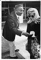 Image of Sam Smith handing woman flier on school levy, April 4, 1977
