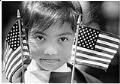 Image of Nyra Sone holding flags at U.S. citizenship ceremony at the Seattle Center, July 4, 1986
